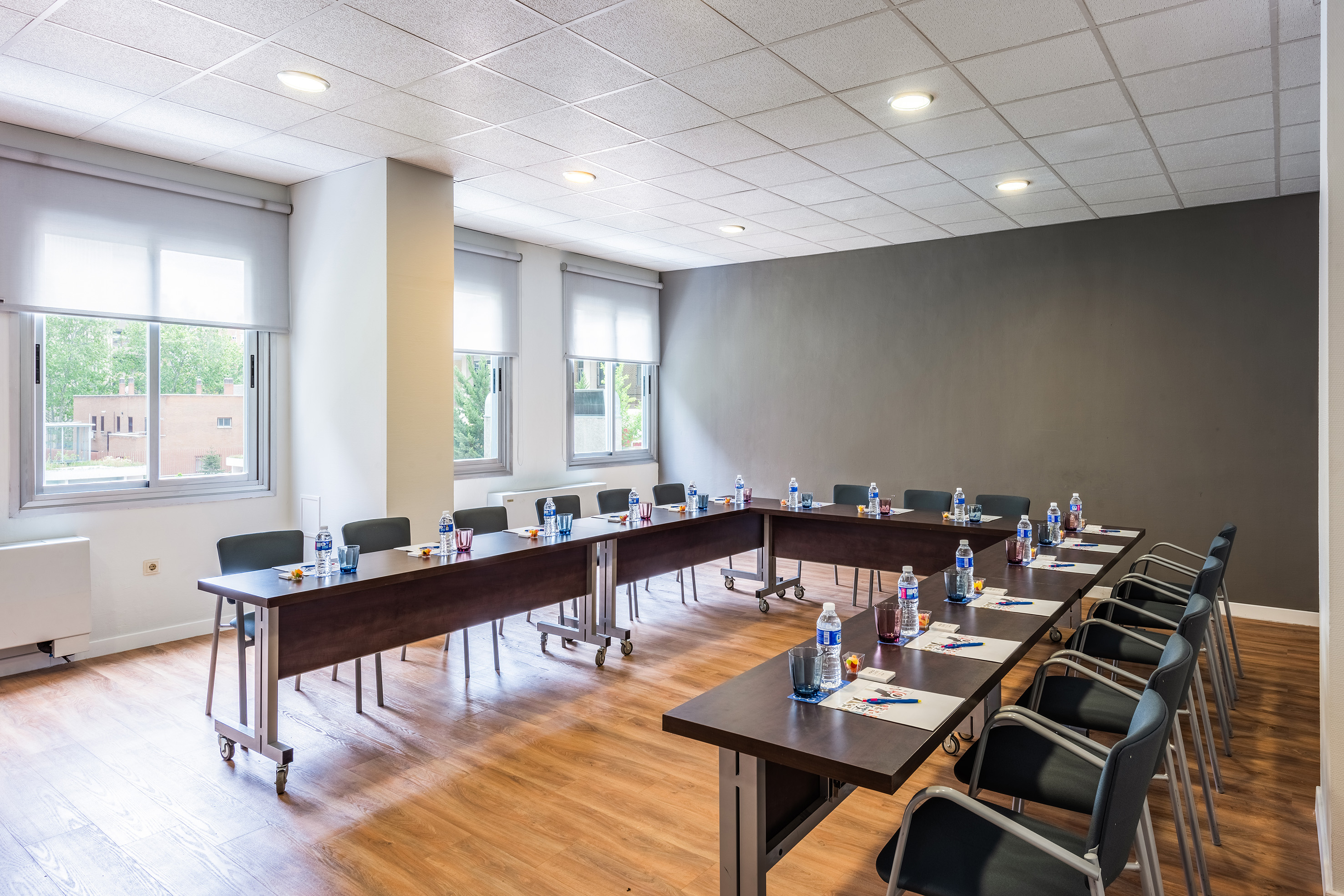 U-shape conference room, tables, chairs, water, and bright windows.