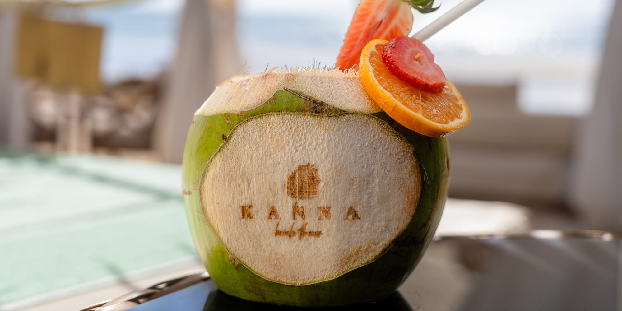 KANNA fresh coconut drink, strawberry, orange garnish, resort setting.
