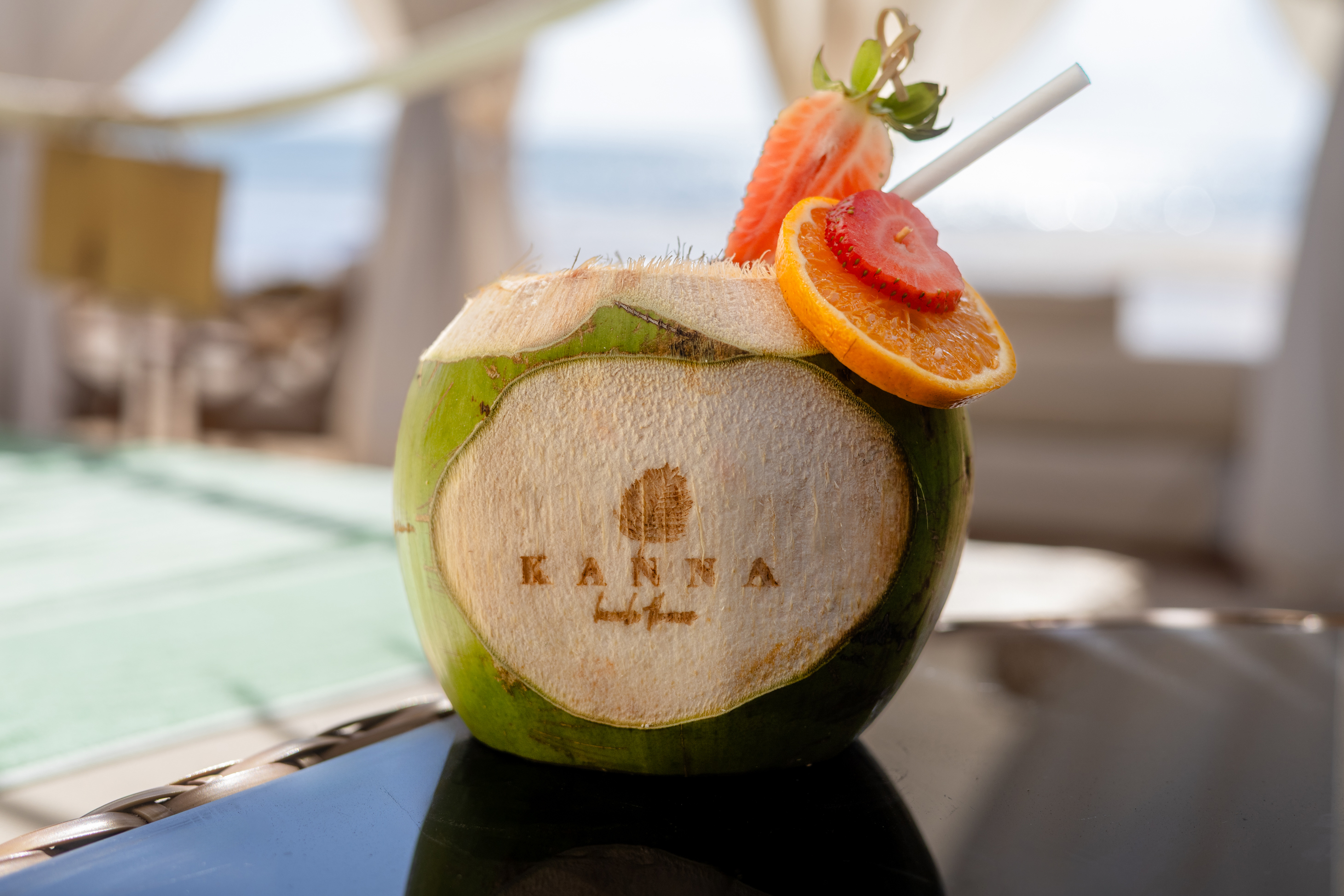 KANNA fresh coconut drink, strawberry, orange garnish, resort setting.
