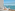 Ocean view balcony with lounge daybed, straw hat, and distant island.