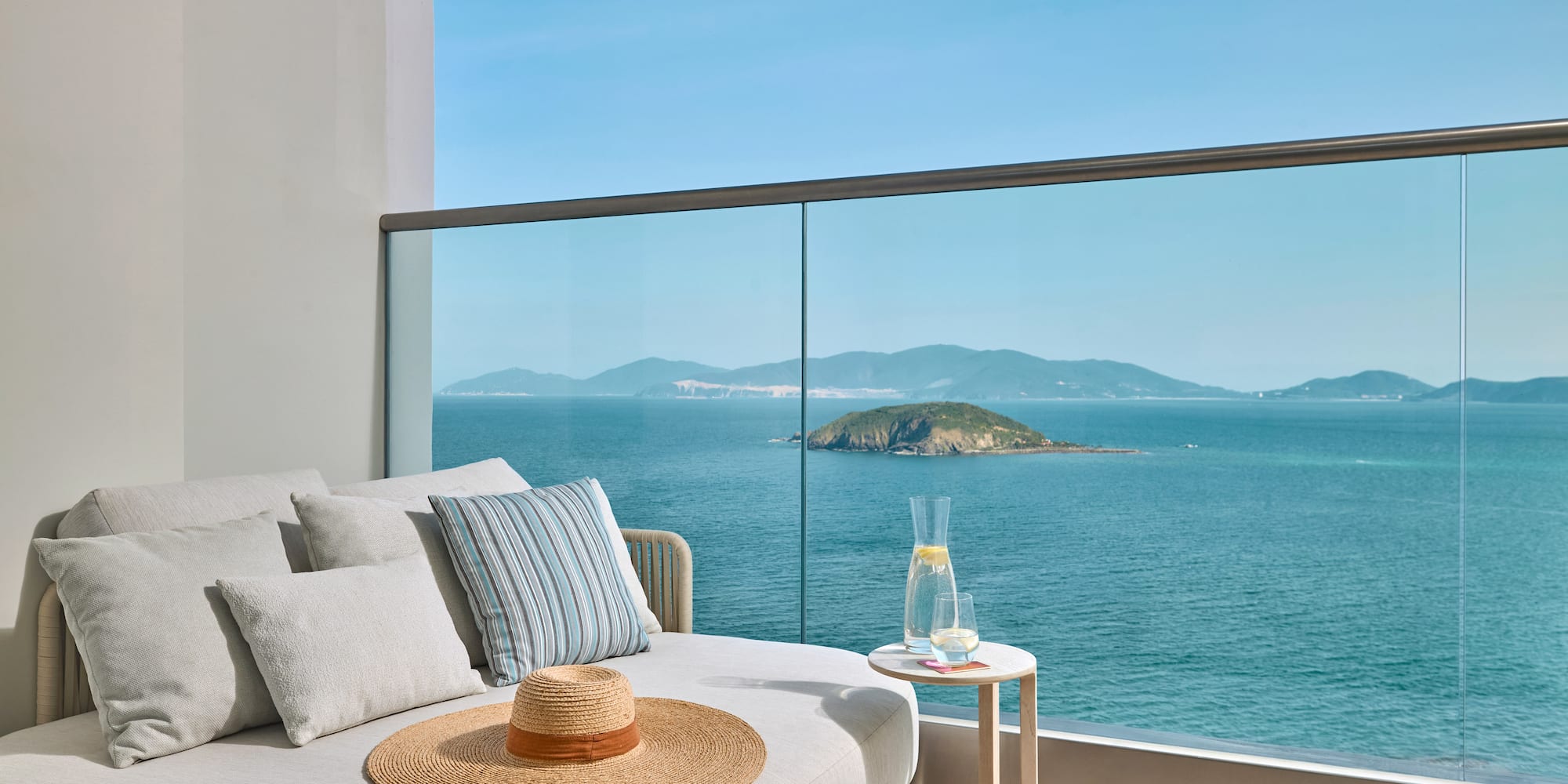 Luxury balcony lounge with panoramic ocean views and distant island.