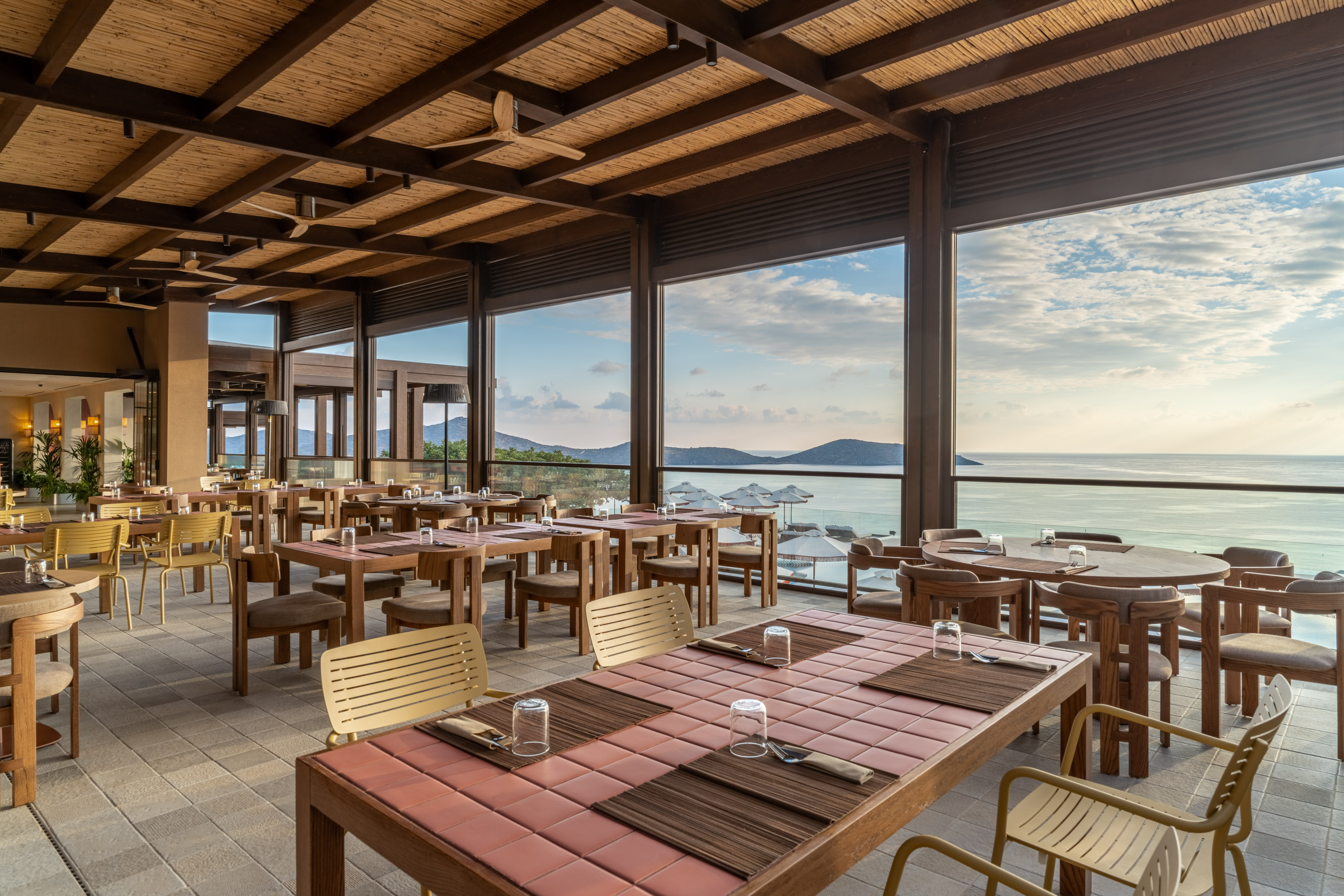 Restaurant terrace with panoramic sea views and set dining tables.