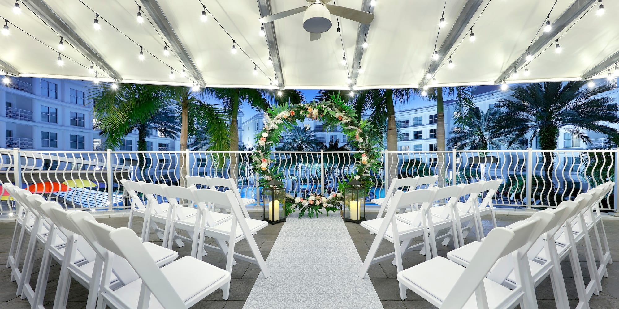 a wedding ceremony area with chairs and a white carpet