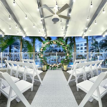 a wedding ceremony area with chairs and a white carpet