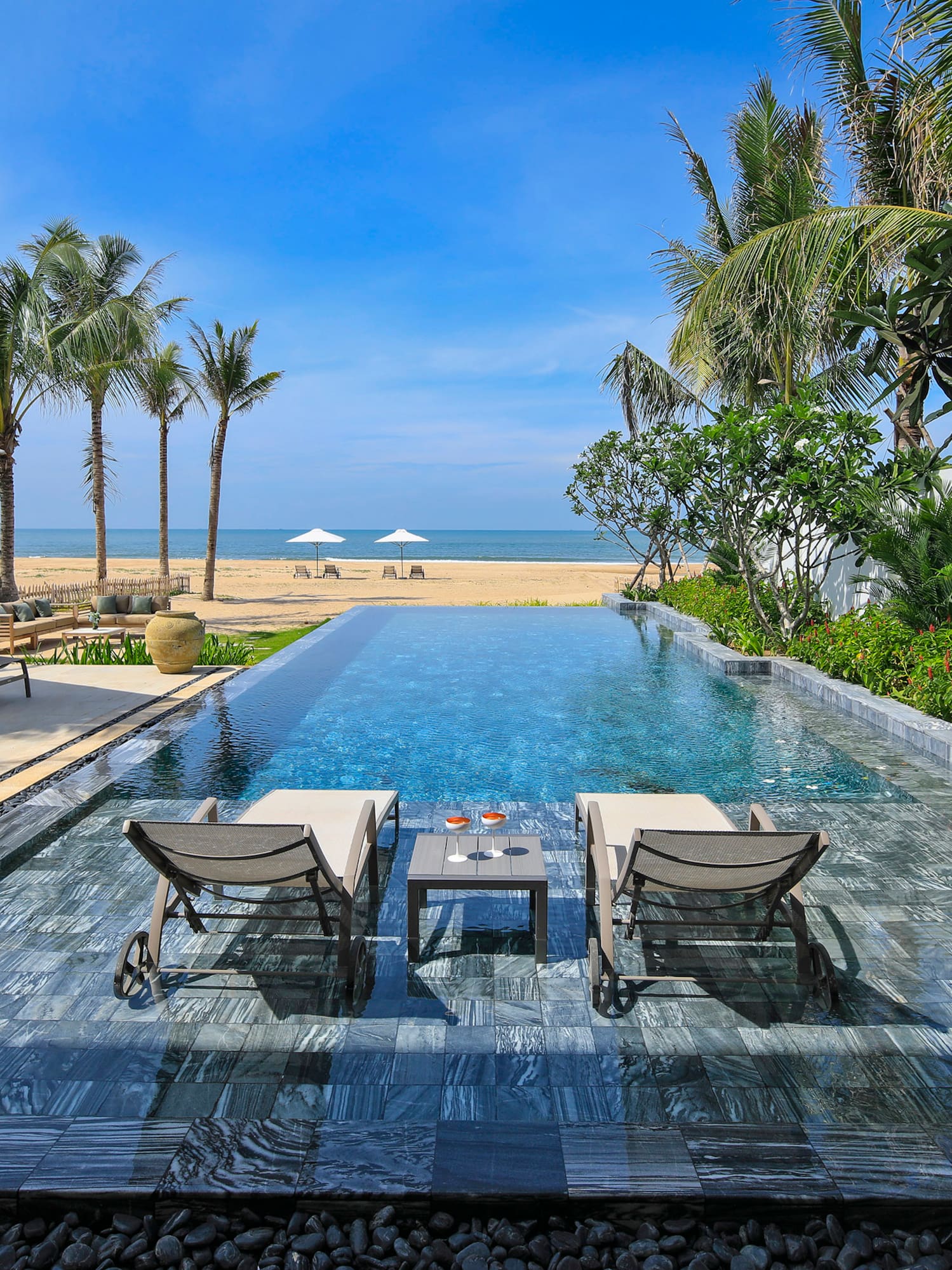 a pool with chairs and a beach in the background