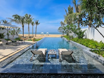 a pool with chairs and a beach in the background