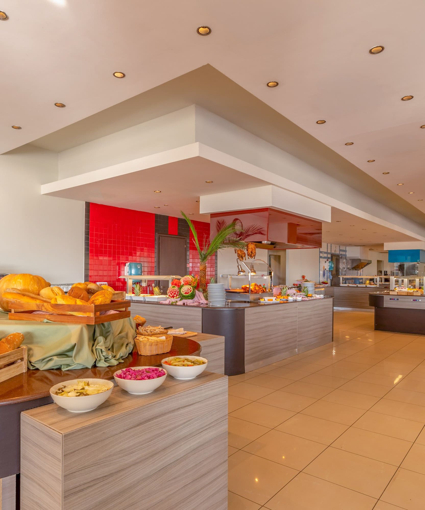 Spacious hotel buffet restaurant with fresh bread, fruit, and diverse food stations.