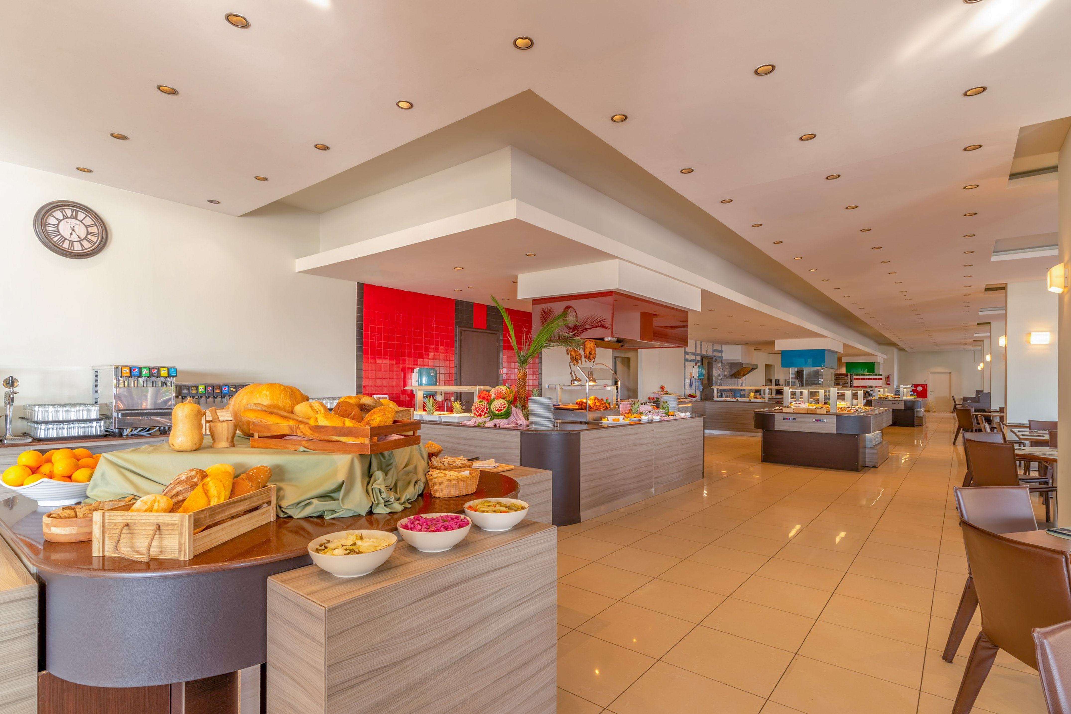 Spacious hotel buffet restaurant with fresh bread, fruit, and diverse food stations.