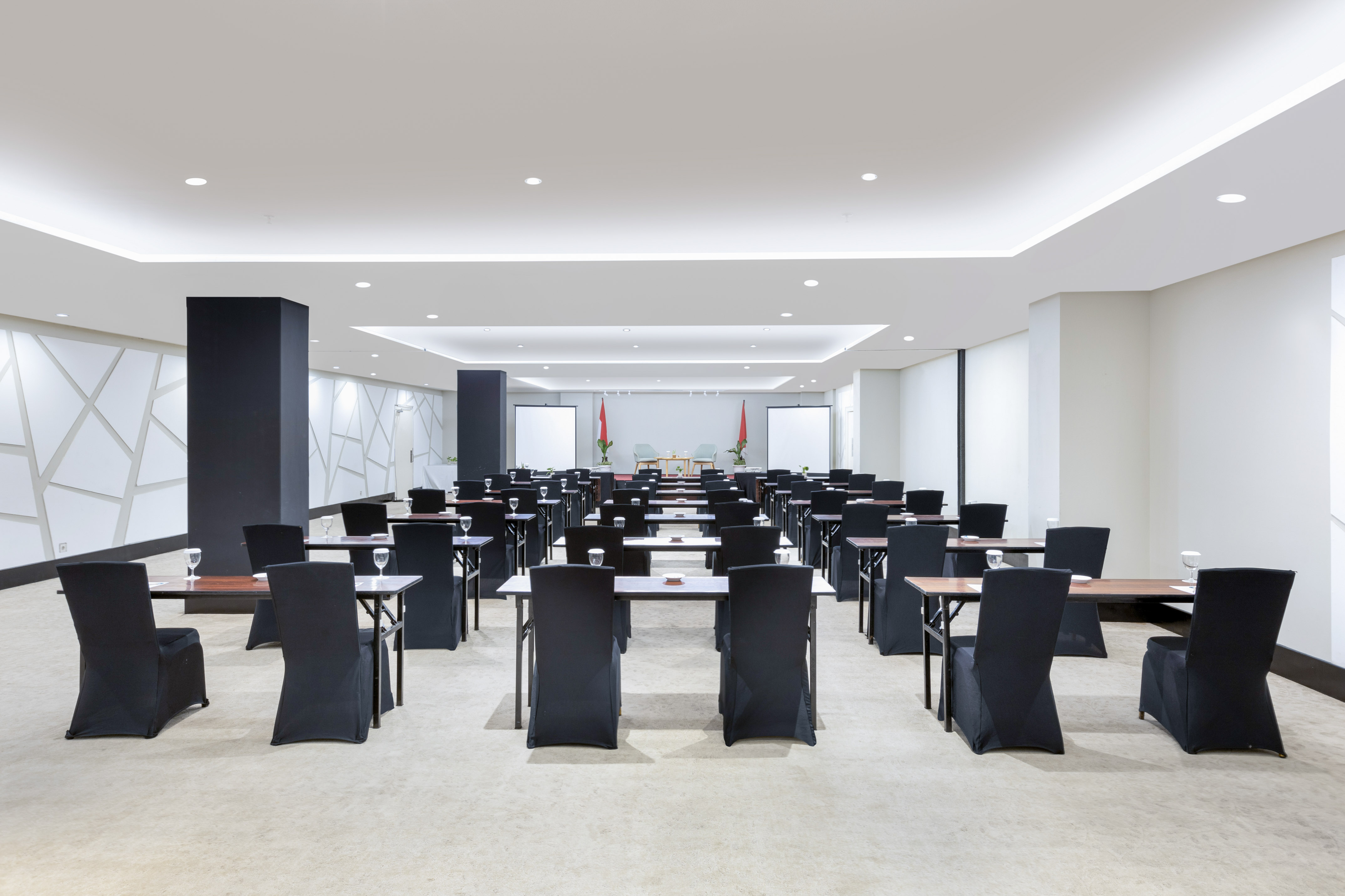 Empty modern conference room with black chairs, tables, and screens.