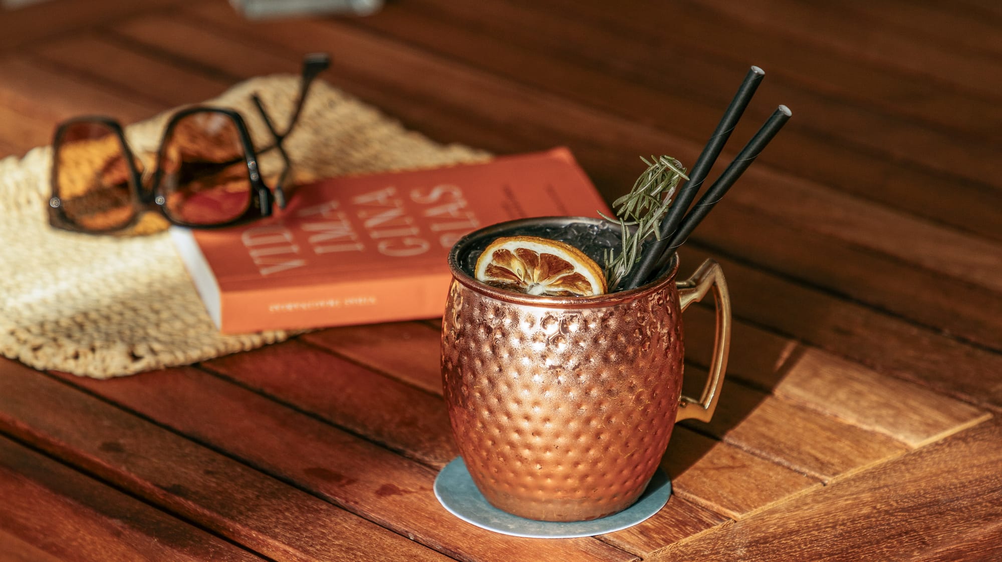 a copper mug with straws and a lemon slice on a wooden table