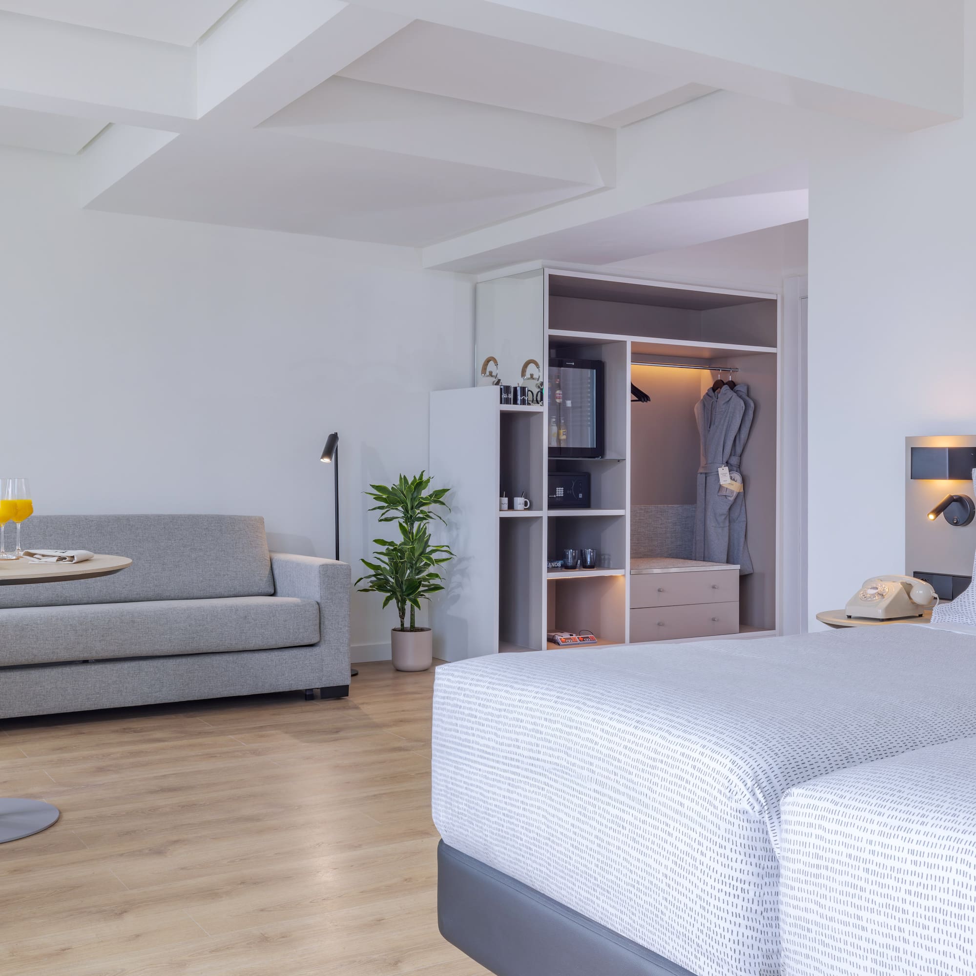 Suite de hotel moderna con camas, sofá, mesa y armario empotrado.