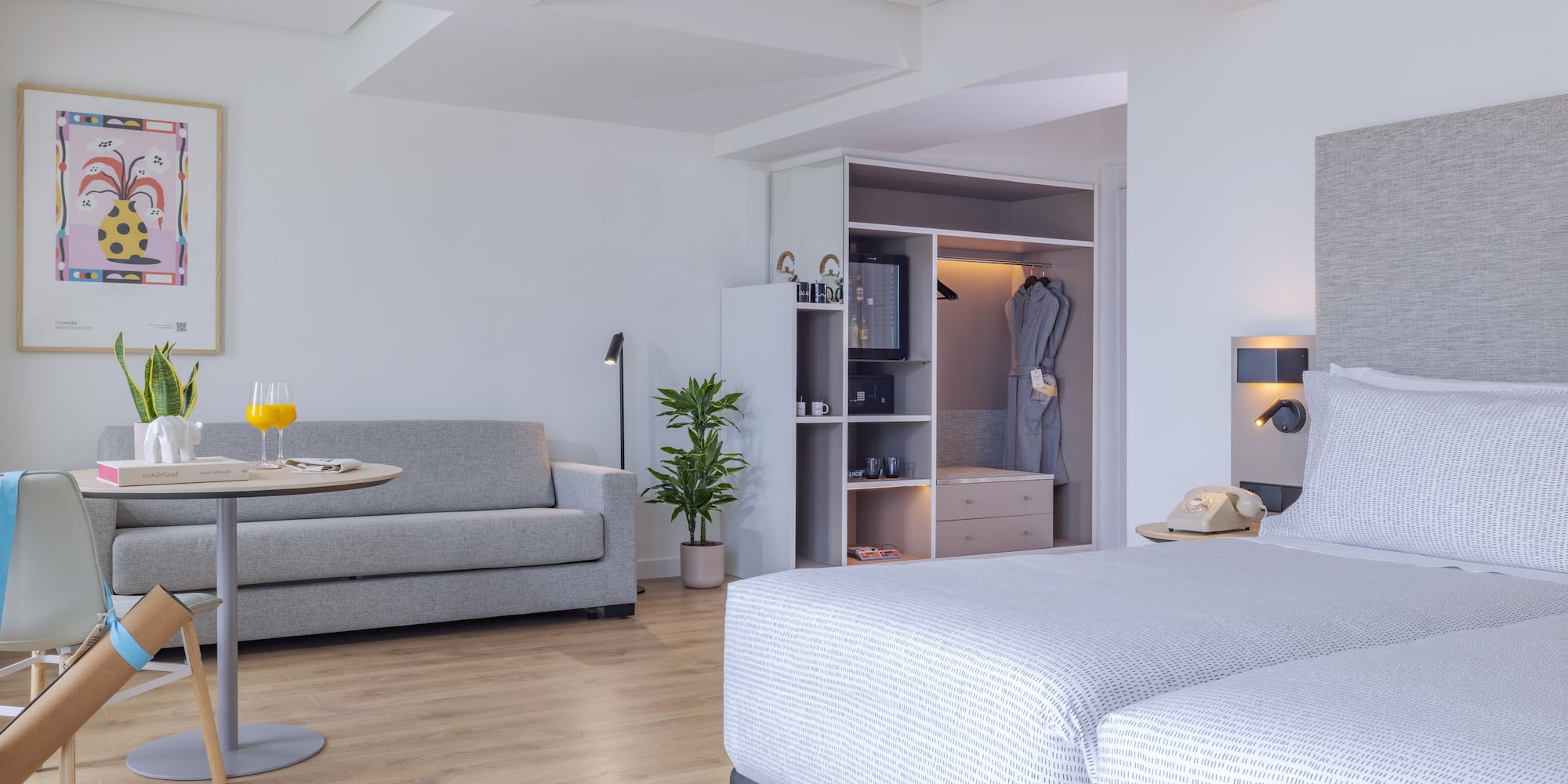 Suite de hotel moderna con camas, sofá, mesa y armario empotrado.