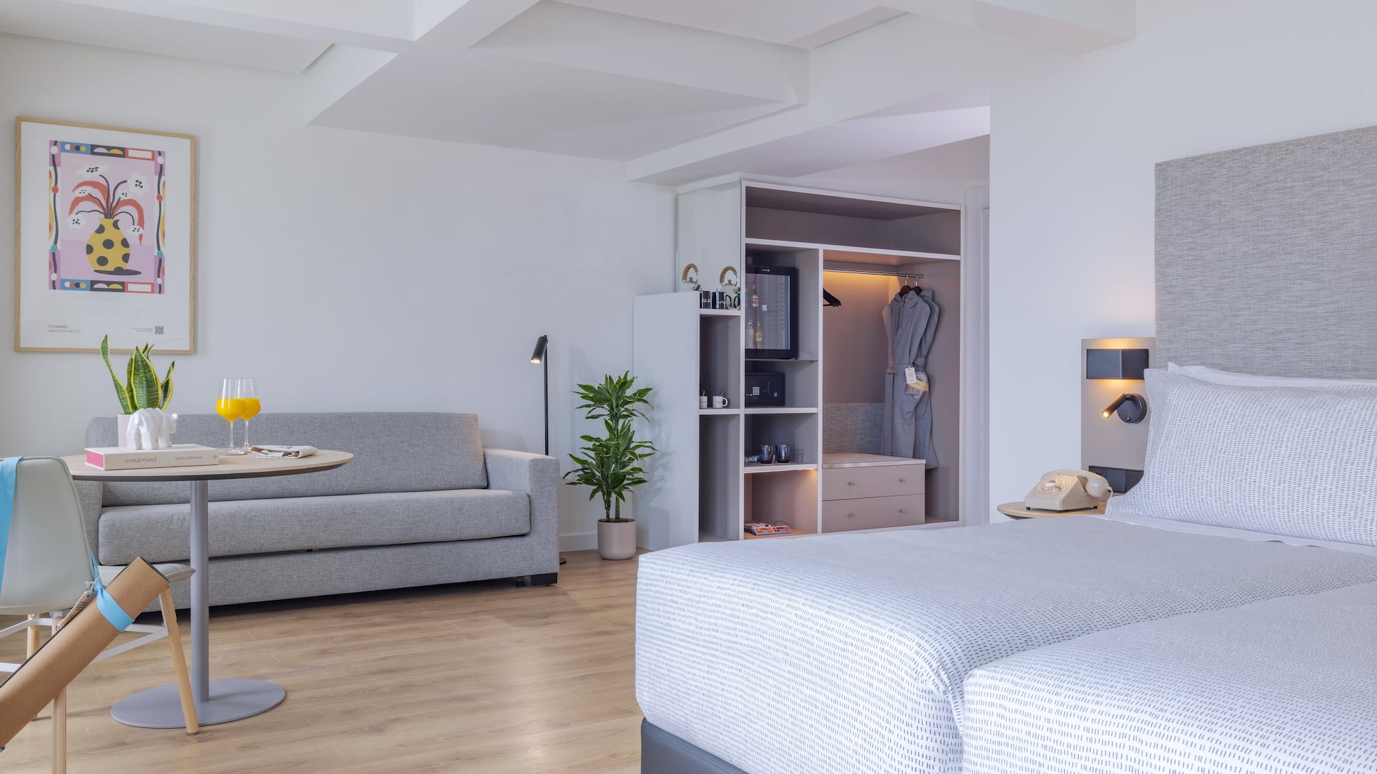 Suite de hotel moderna con camas, sofá, mesa y armario empotrado.