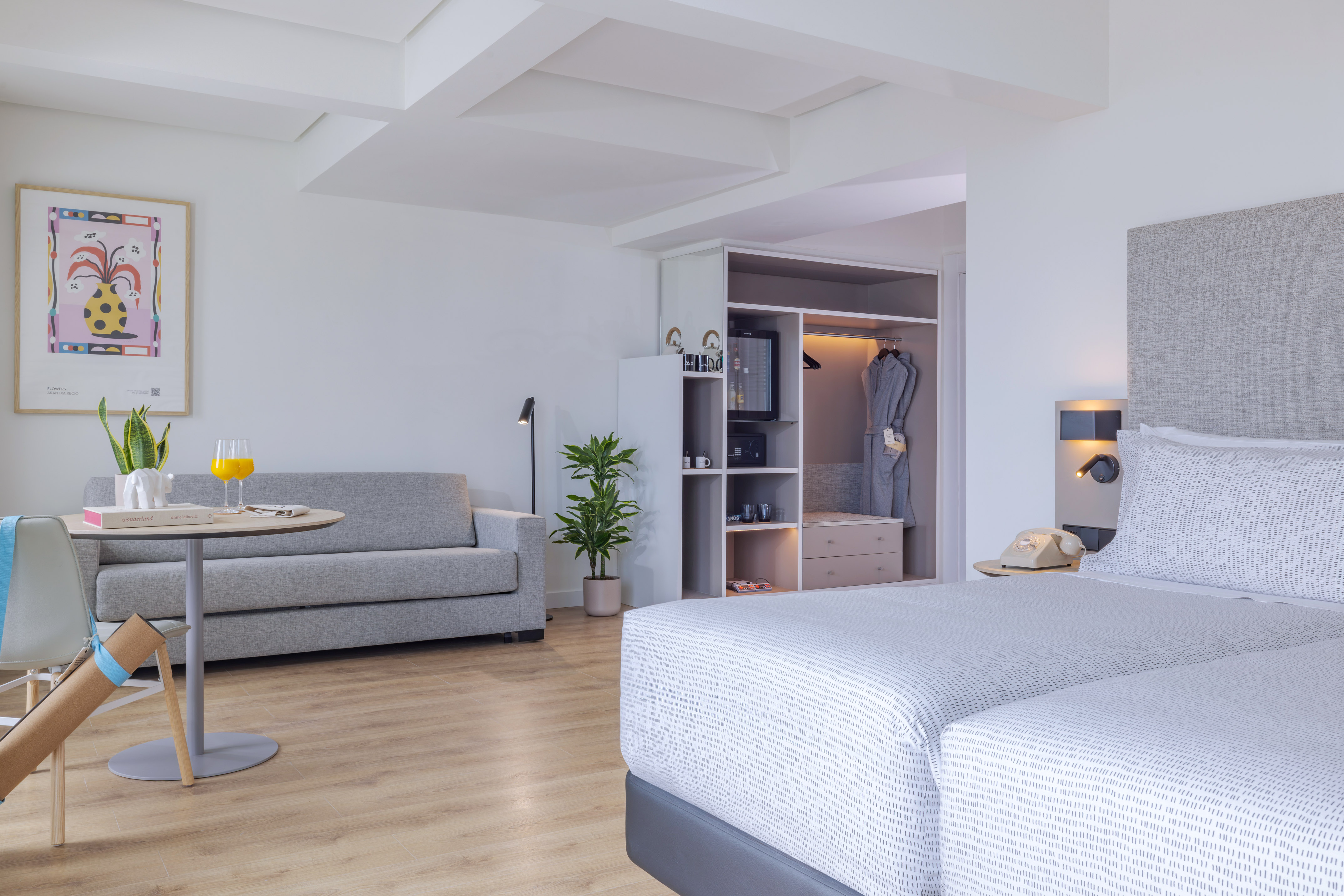 Suite de hotel moderna con camas, sofá, mesa y armario empotrado.