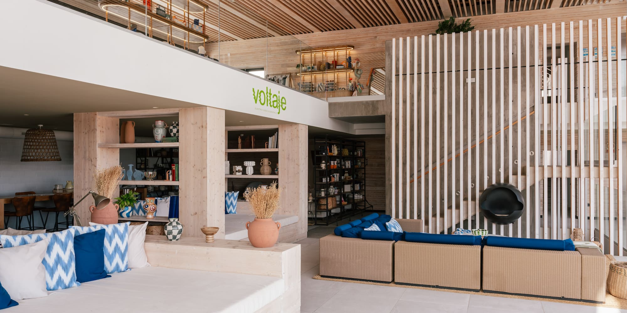 Voltaje modern lounge interior with wood slat ceiling, concrete, and blue decor.