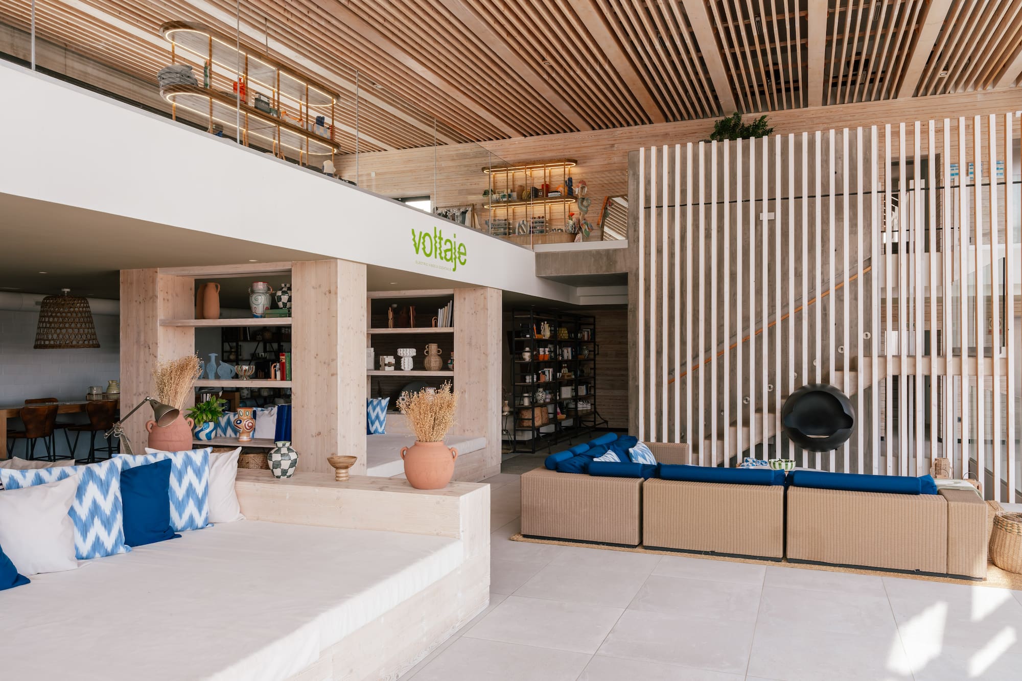 Voltaje modern lounge interior with wood slat ceiling, concrete, and blue decor.