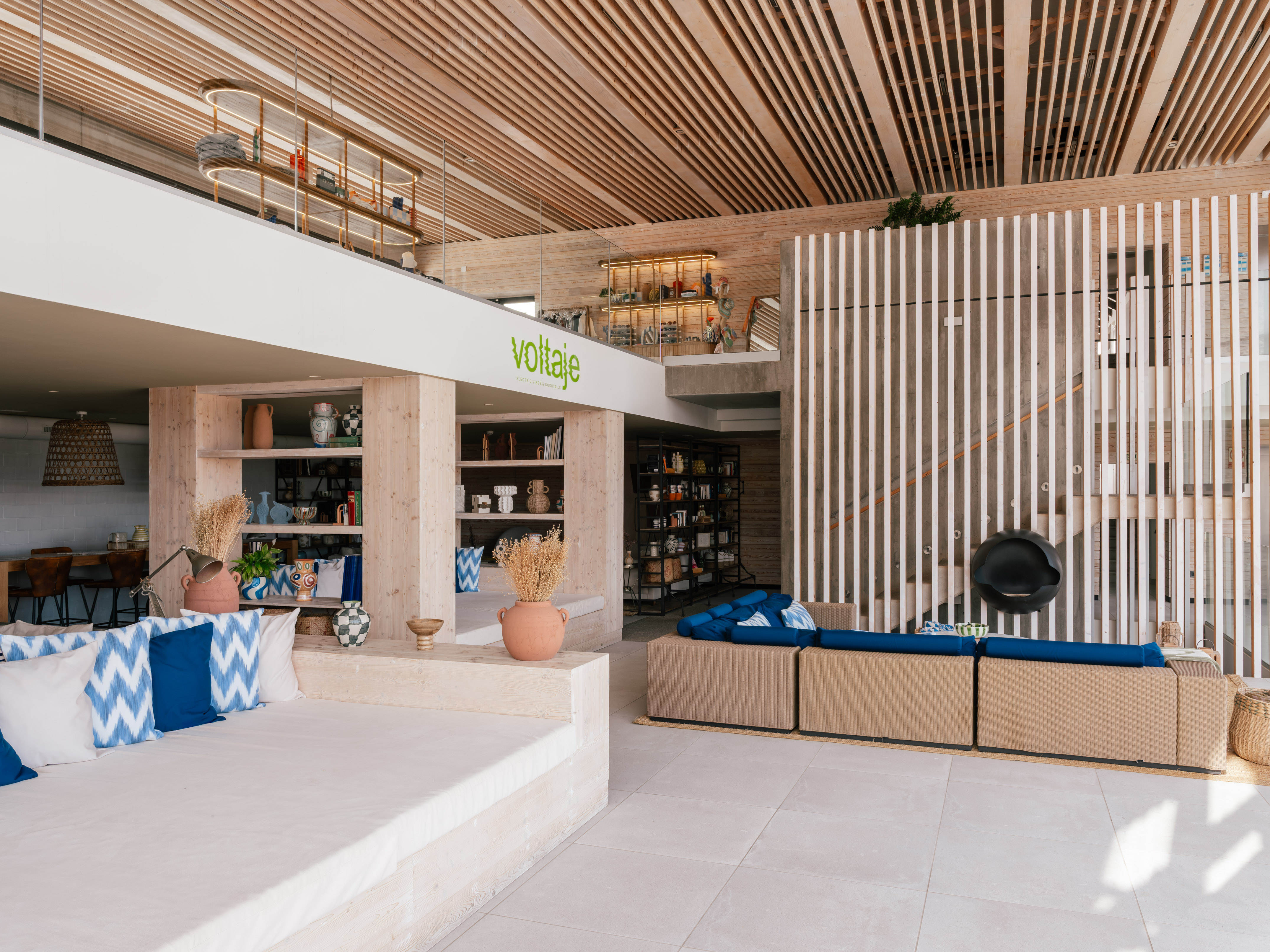 Voltaje modern lounge interior with wood slat ceiling, concrete, and blue decor.