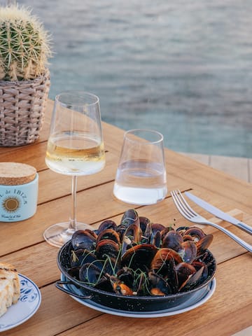 a plate of clams and wine glasses on a table