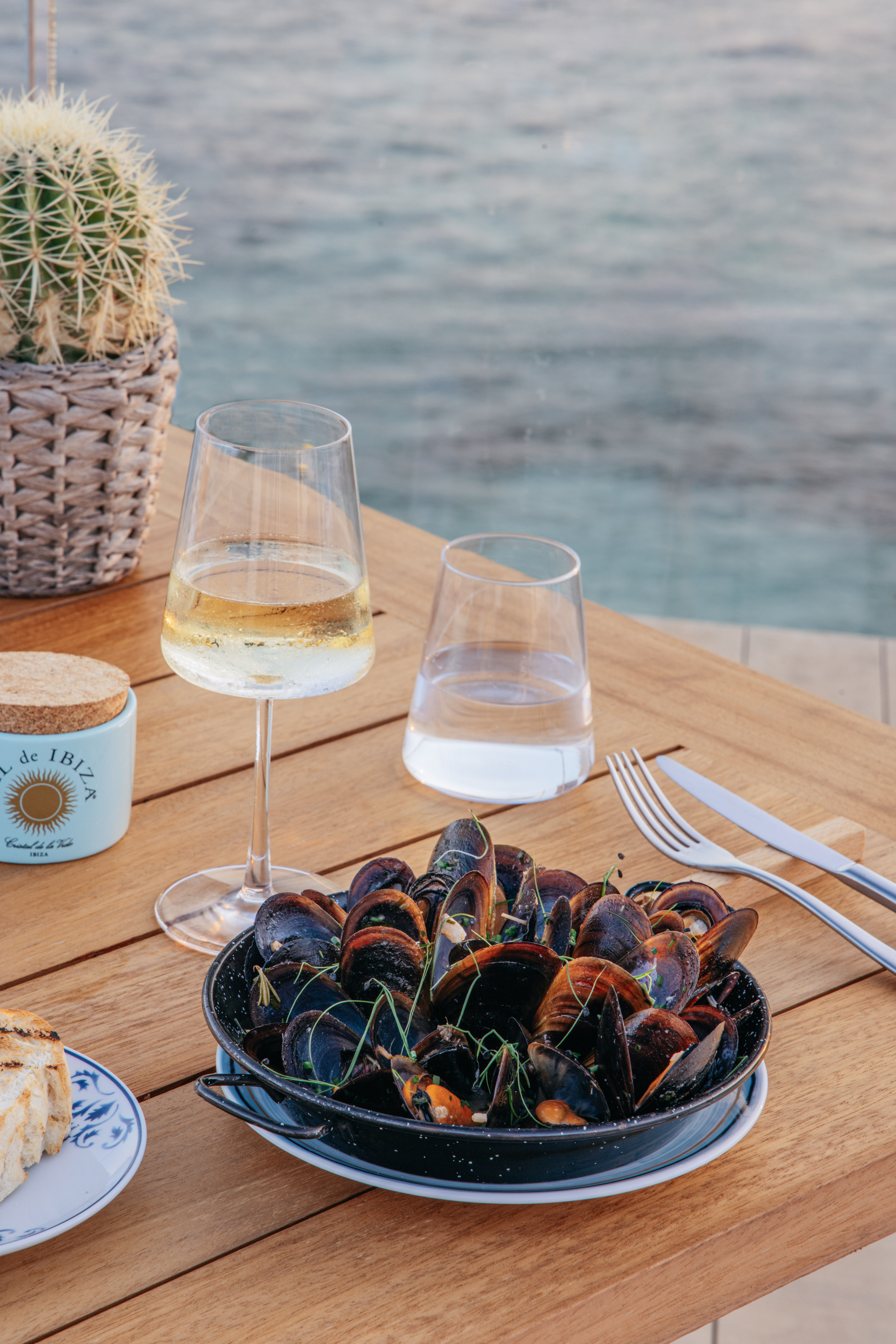 a plate of clams and wine glasses on a table