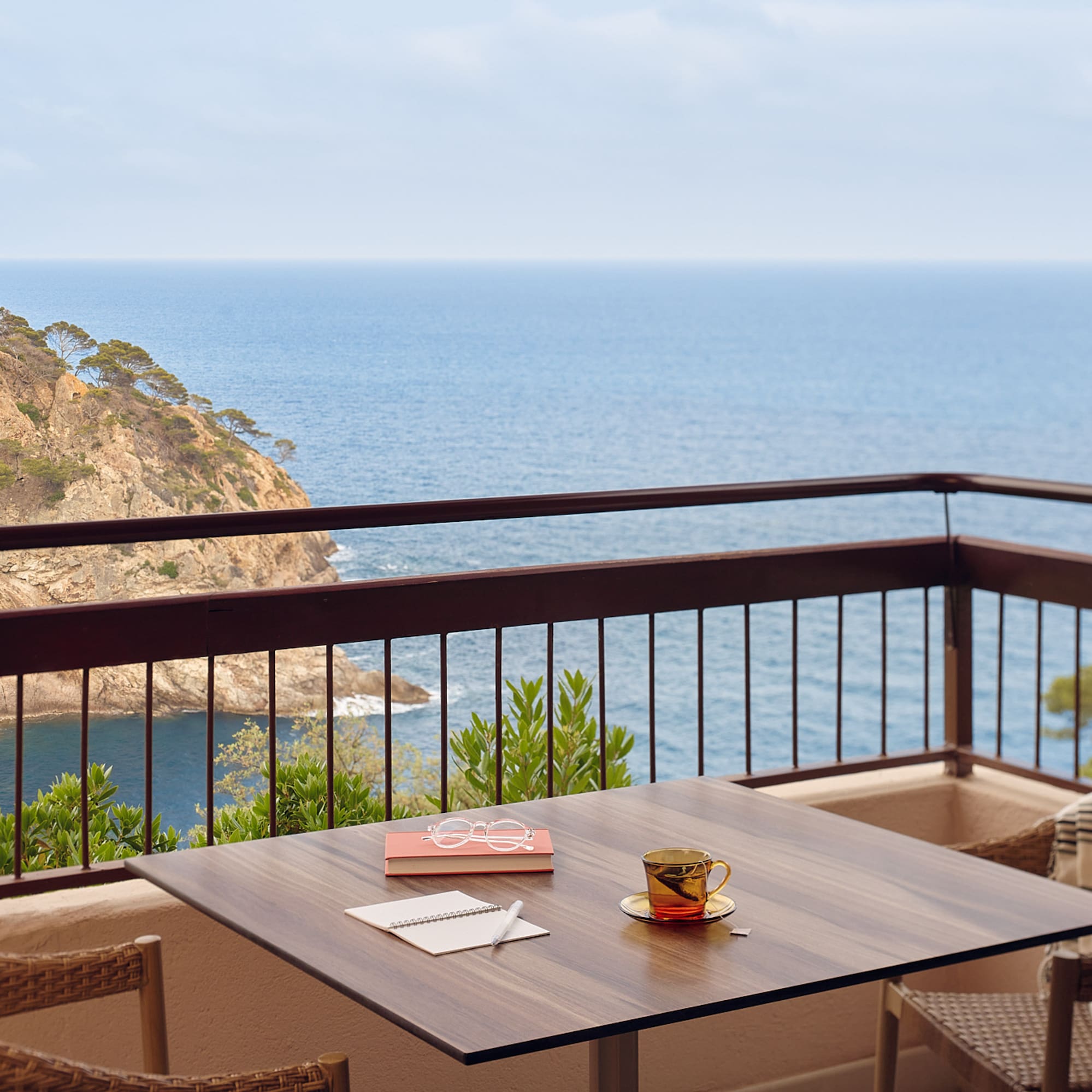 a table and chairs on a balcony overlooking the ocean