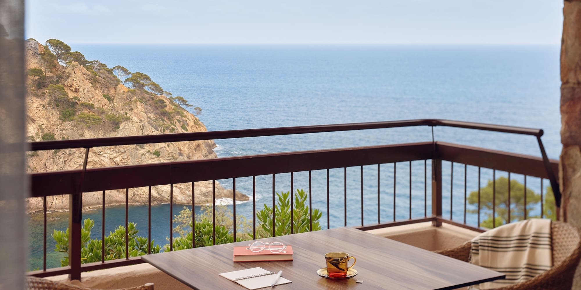 a table and chairs on a balcony overlooking the ocean