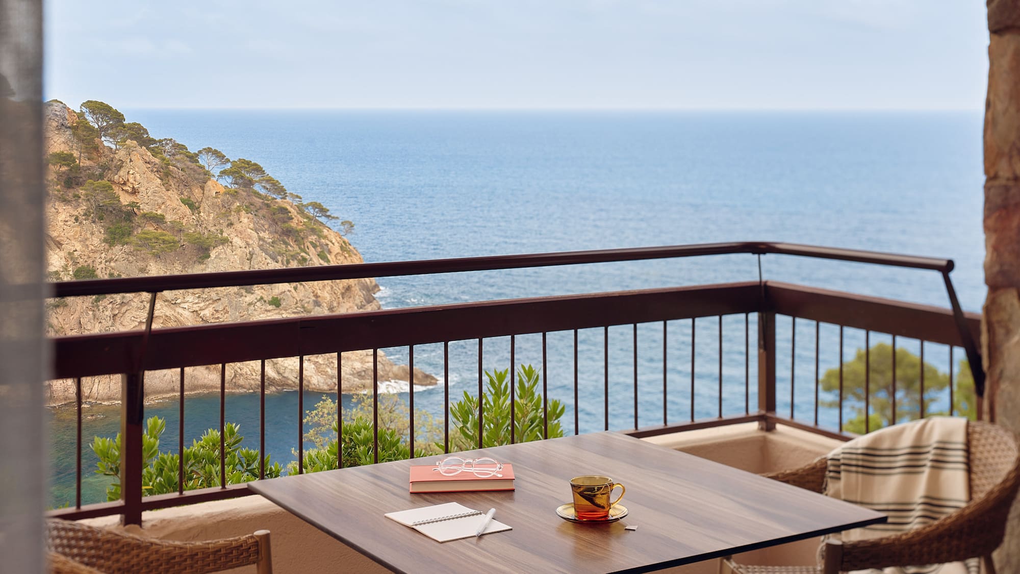 a table and chairs on a balcony overlooking the ocean