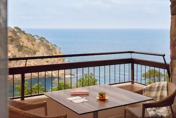 a table and chairs on a balcony overlooking the ocean