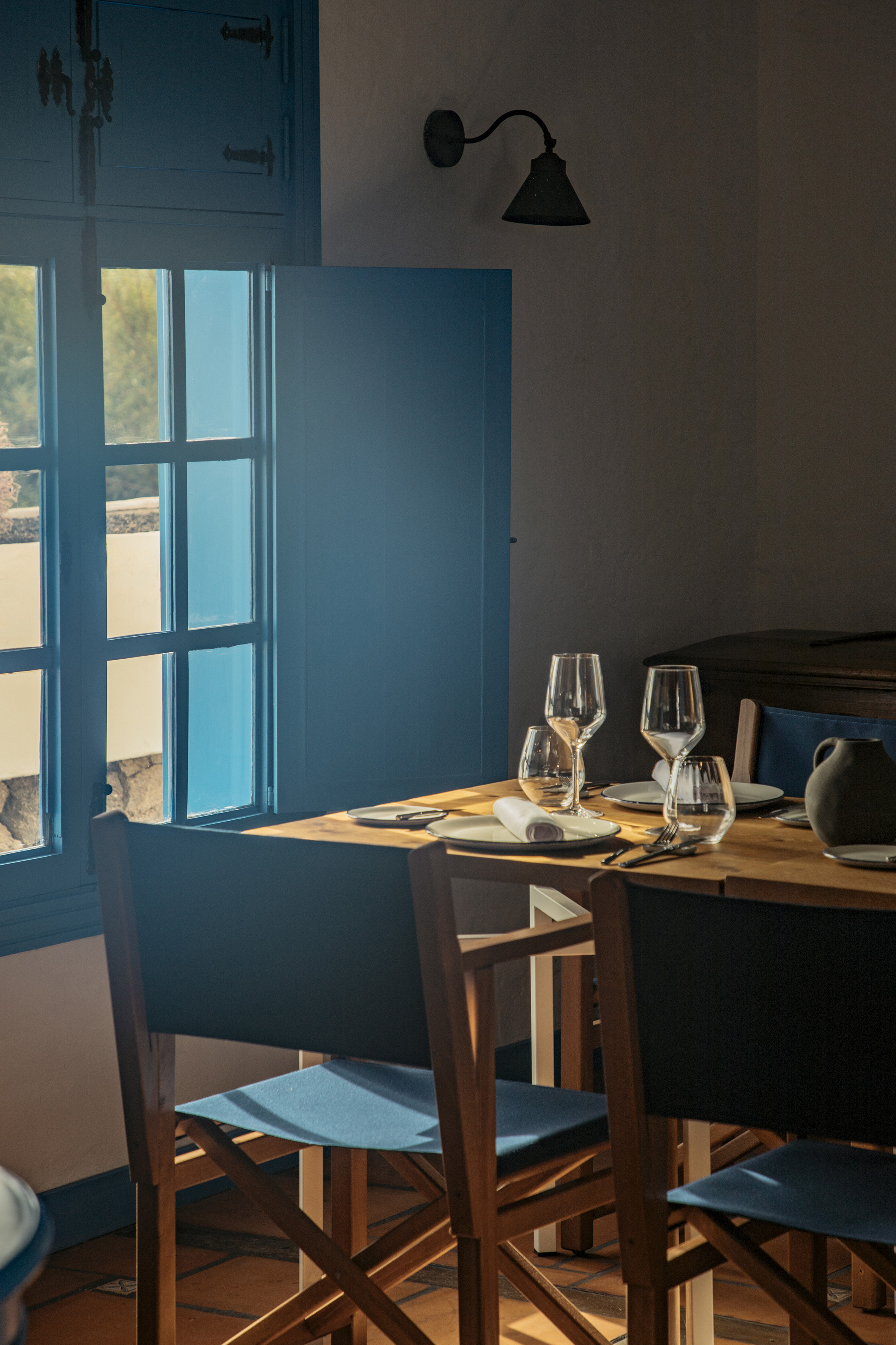 Mediterranean restaurant interior with set dining table and blue window.