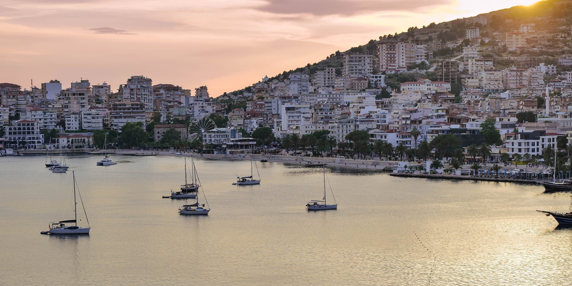 a group of boats in a body of water with buildings in the background