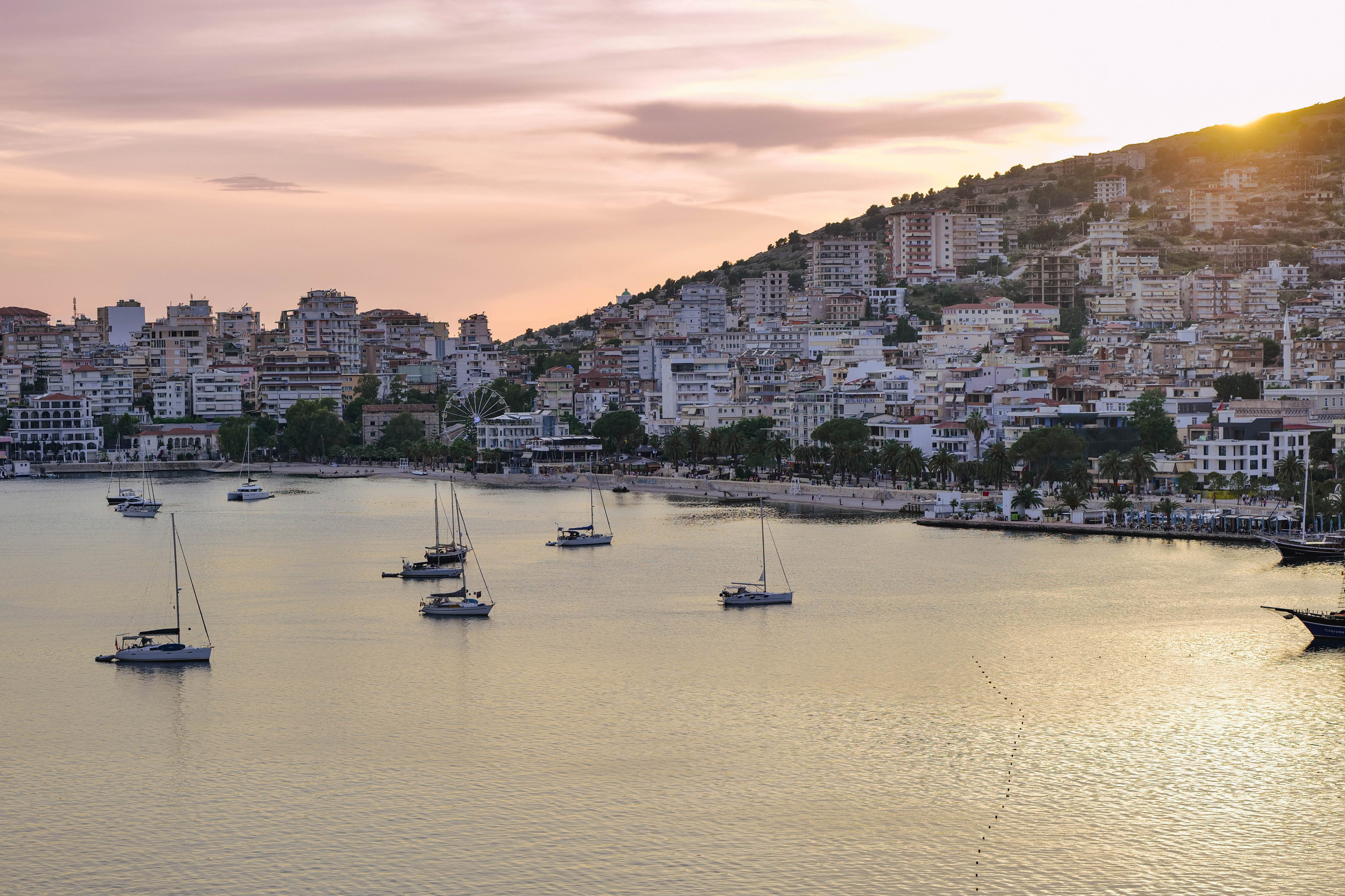 a group of boats in a body of water with buildings in the background
