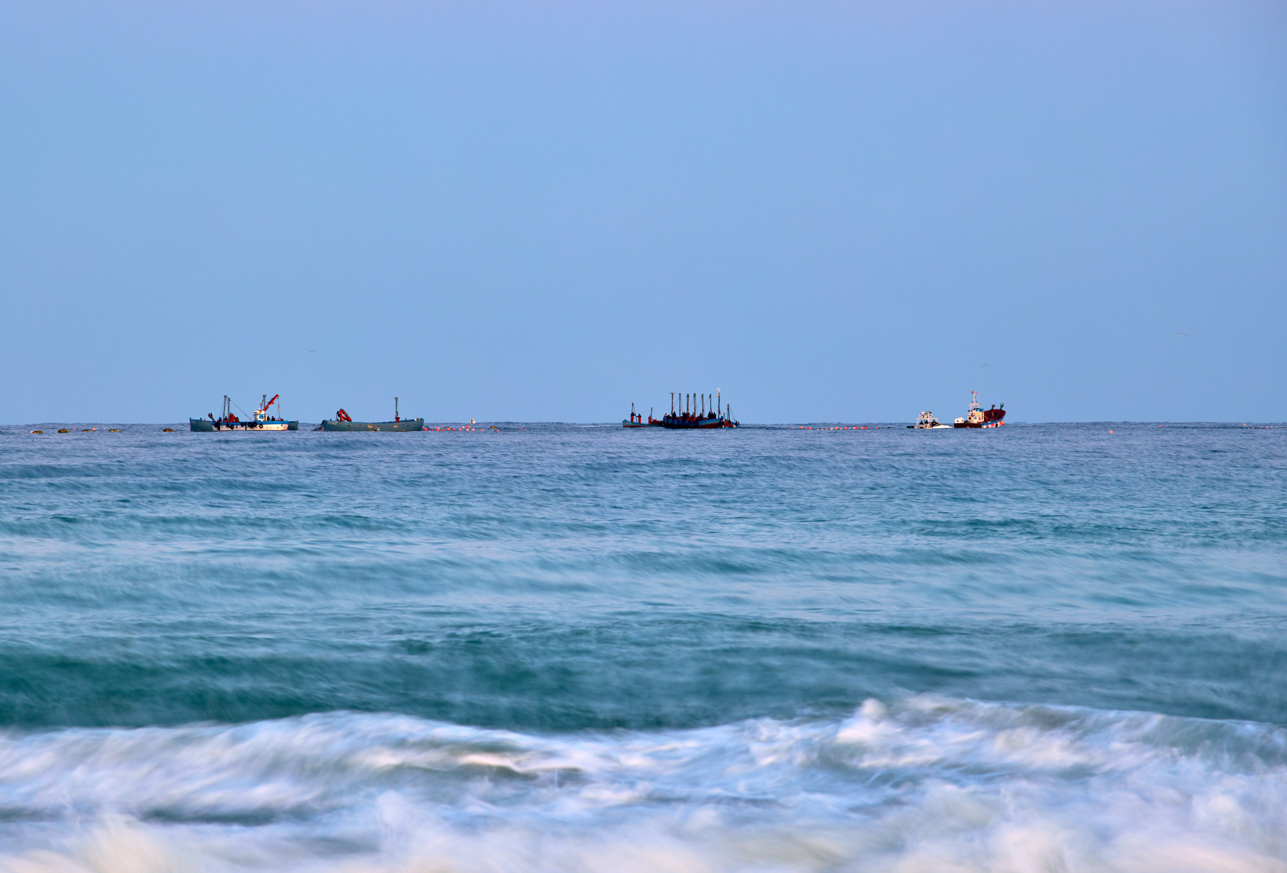 Construction barges and pipeline on the sea with small waves.