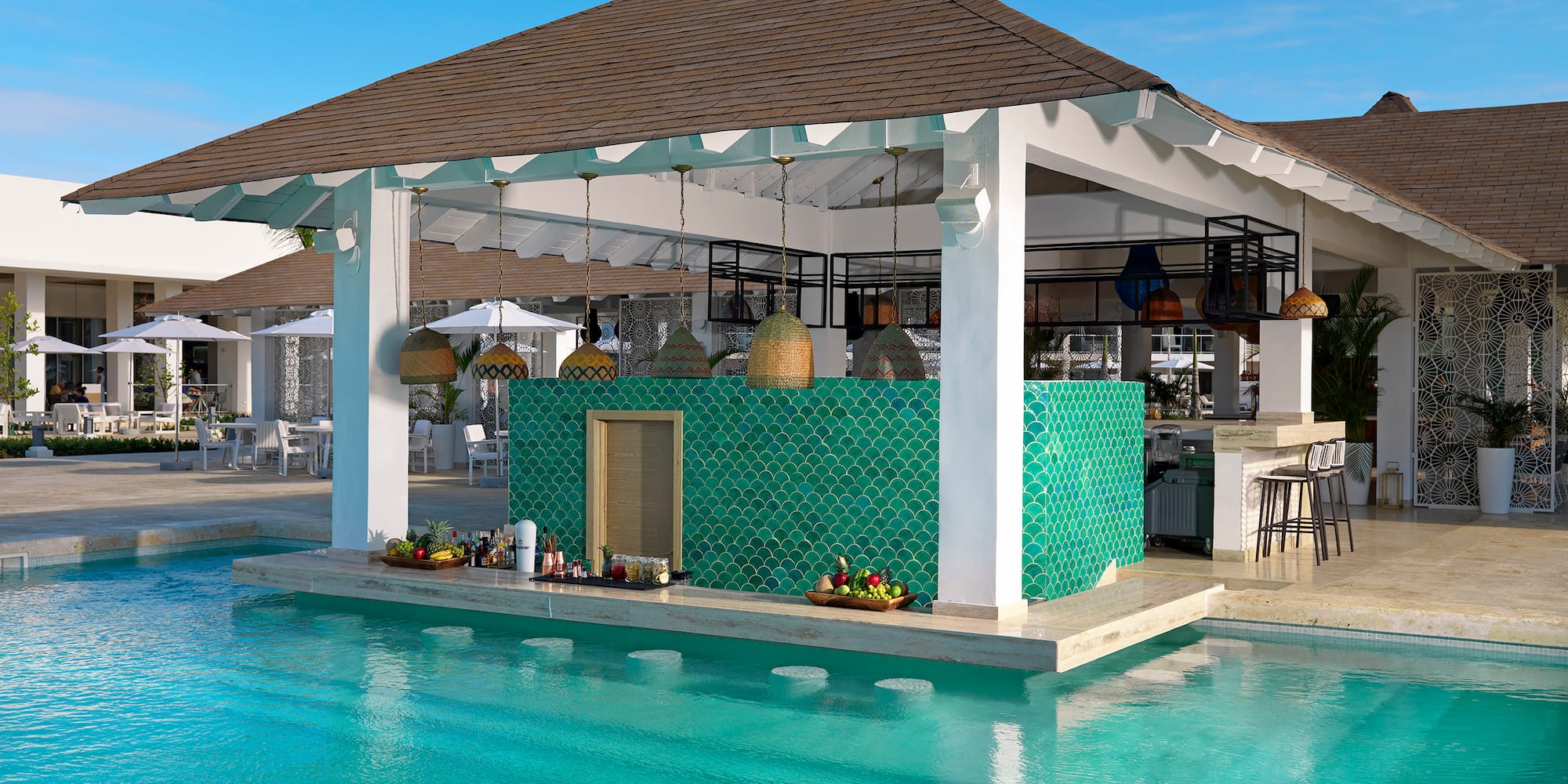 Tropical swim-up bar in a resort pool with green scalloped tiles.