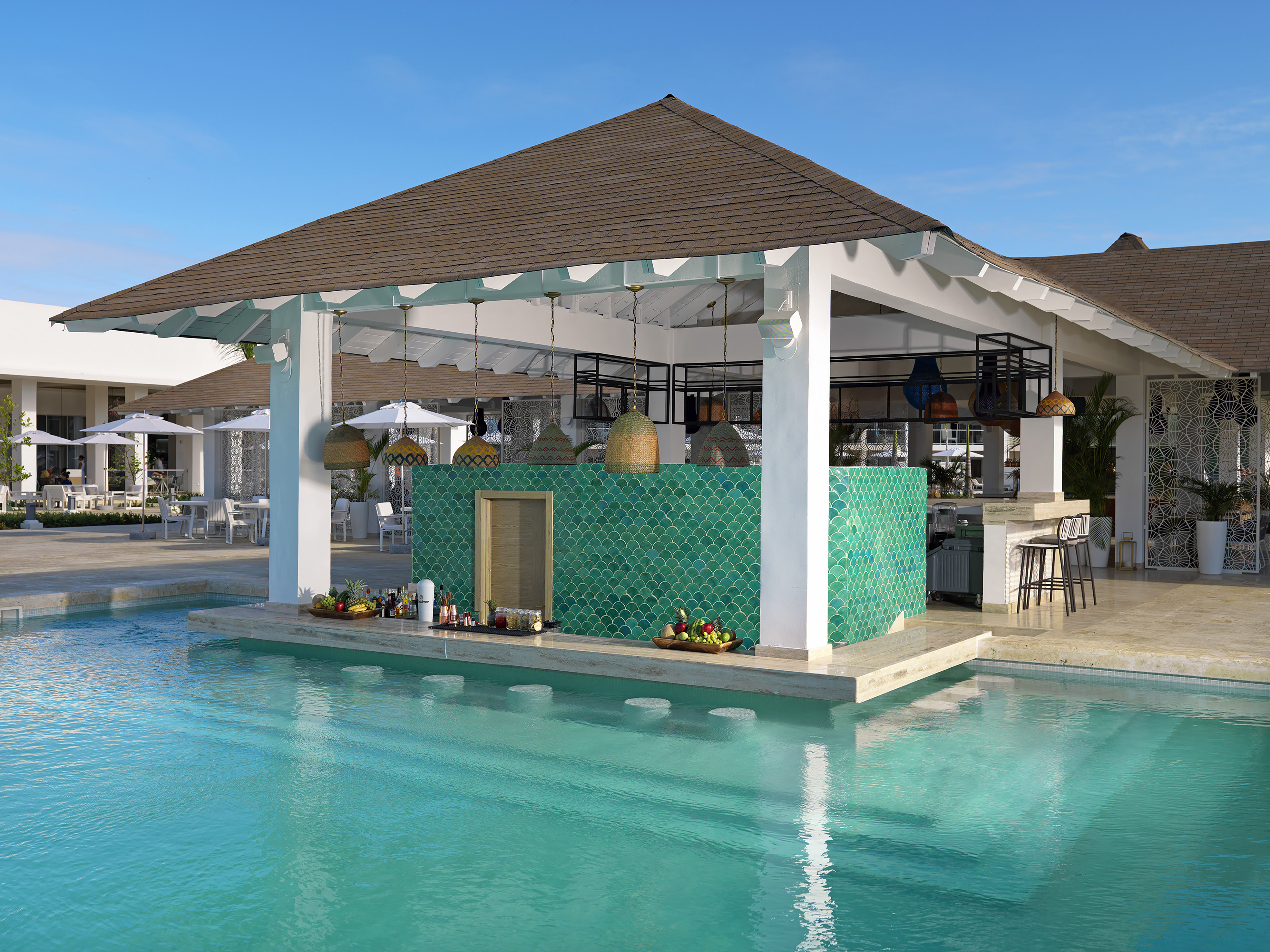 Tropical swim-up bar in a resort pool with green scalloped tiles.