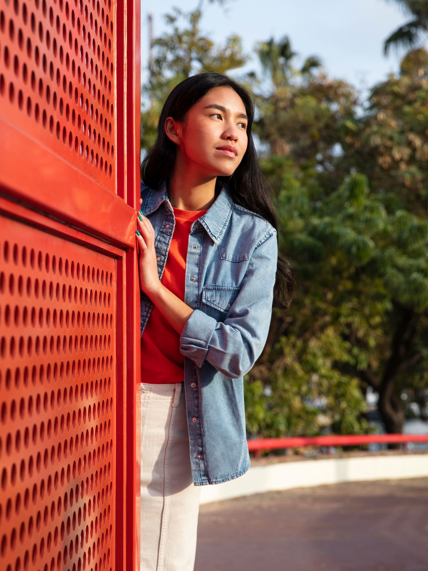 a woman leaning against a red wall