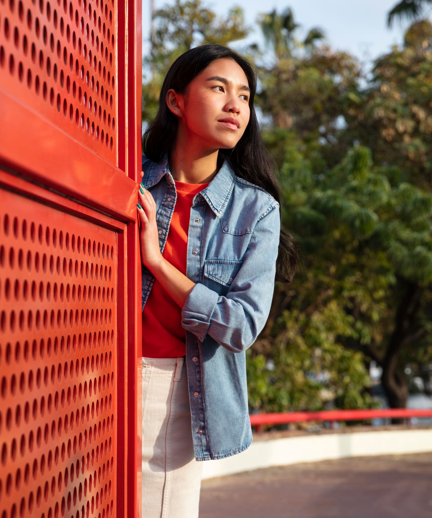 a woman leaning against a red wall