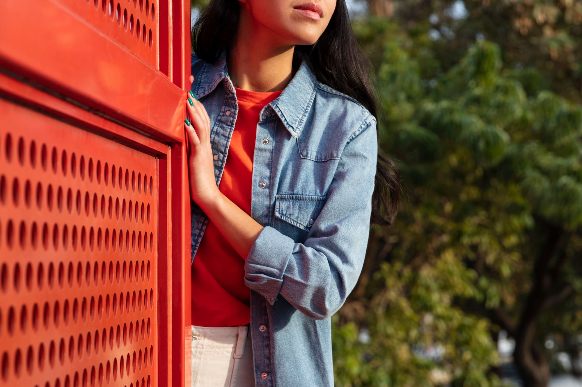 a woman leaning against a red wall