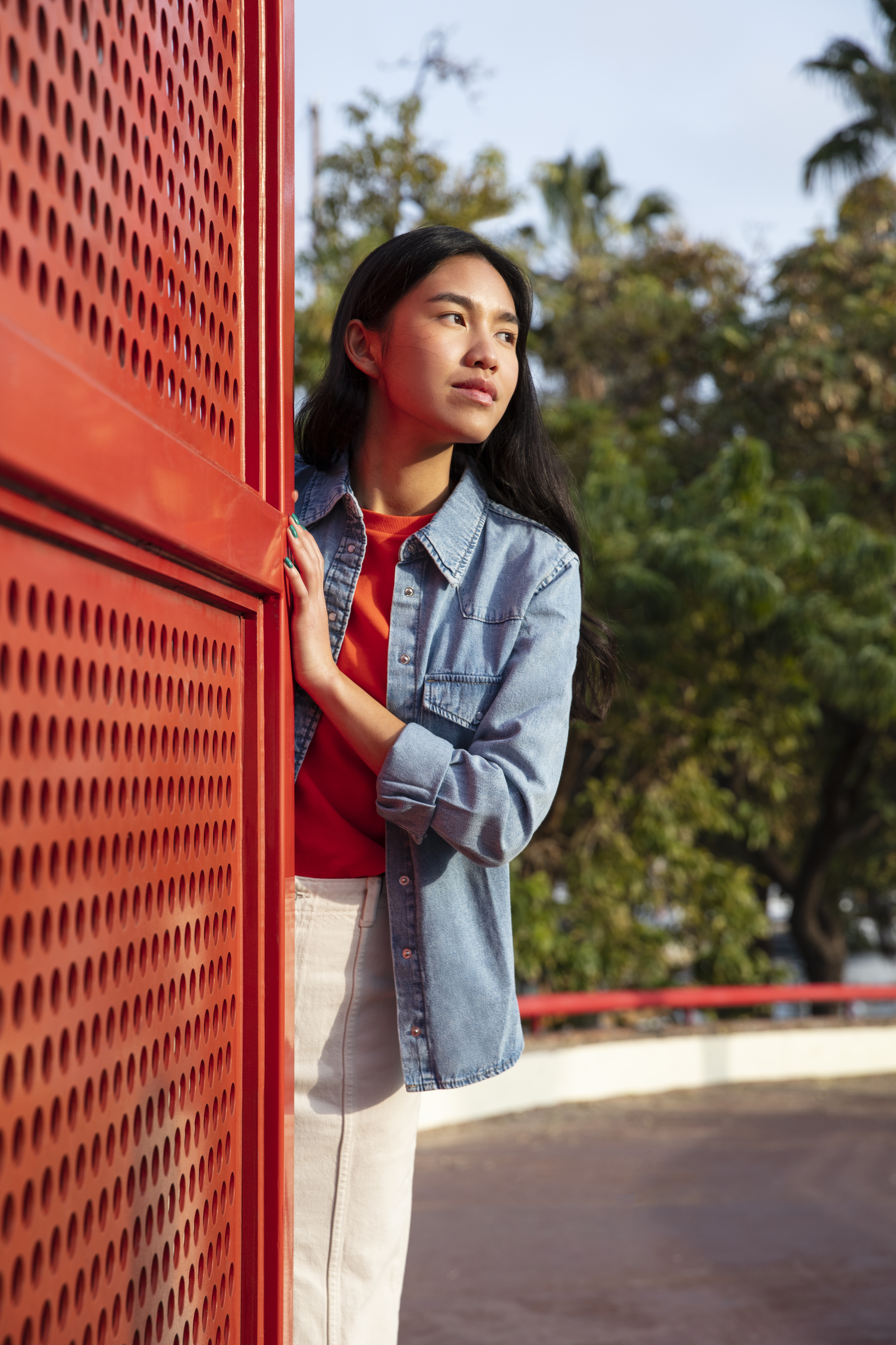 a woman leaning against a red wall
