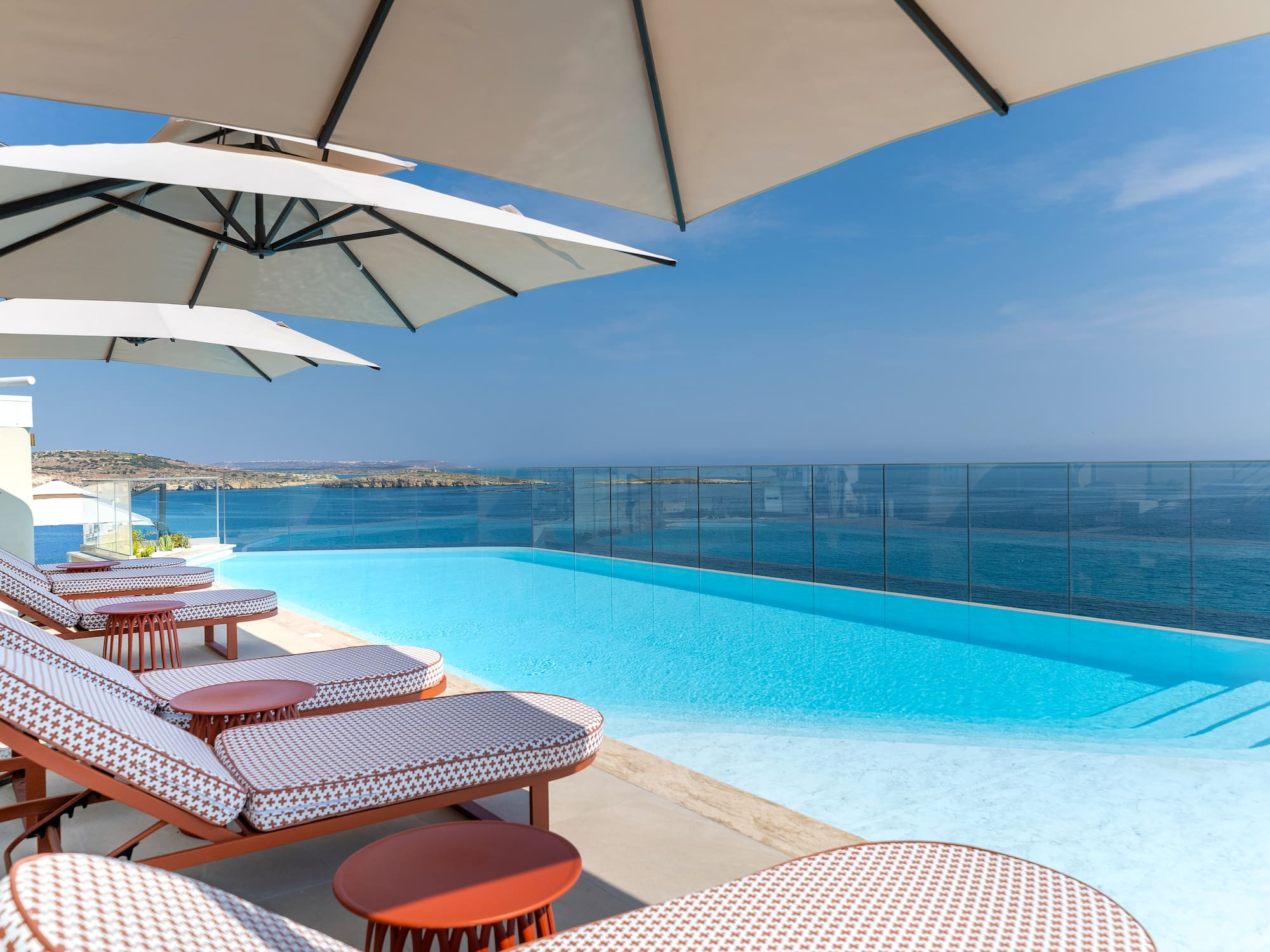 Luxury infinity pool with ocean view, sun loungers, and umbrellas.