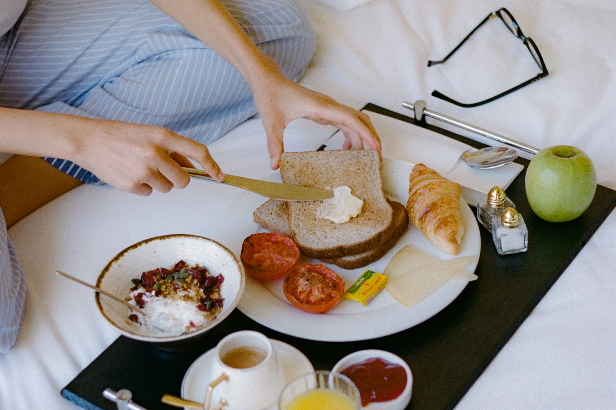 a person cutting bread with a knife on a tray with food