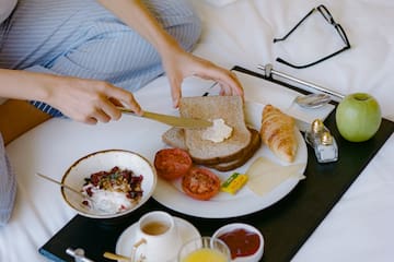 a person cutting bread with a knife on a tray with food