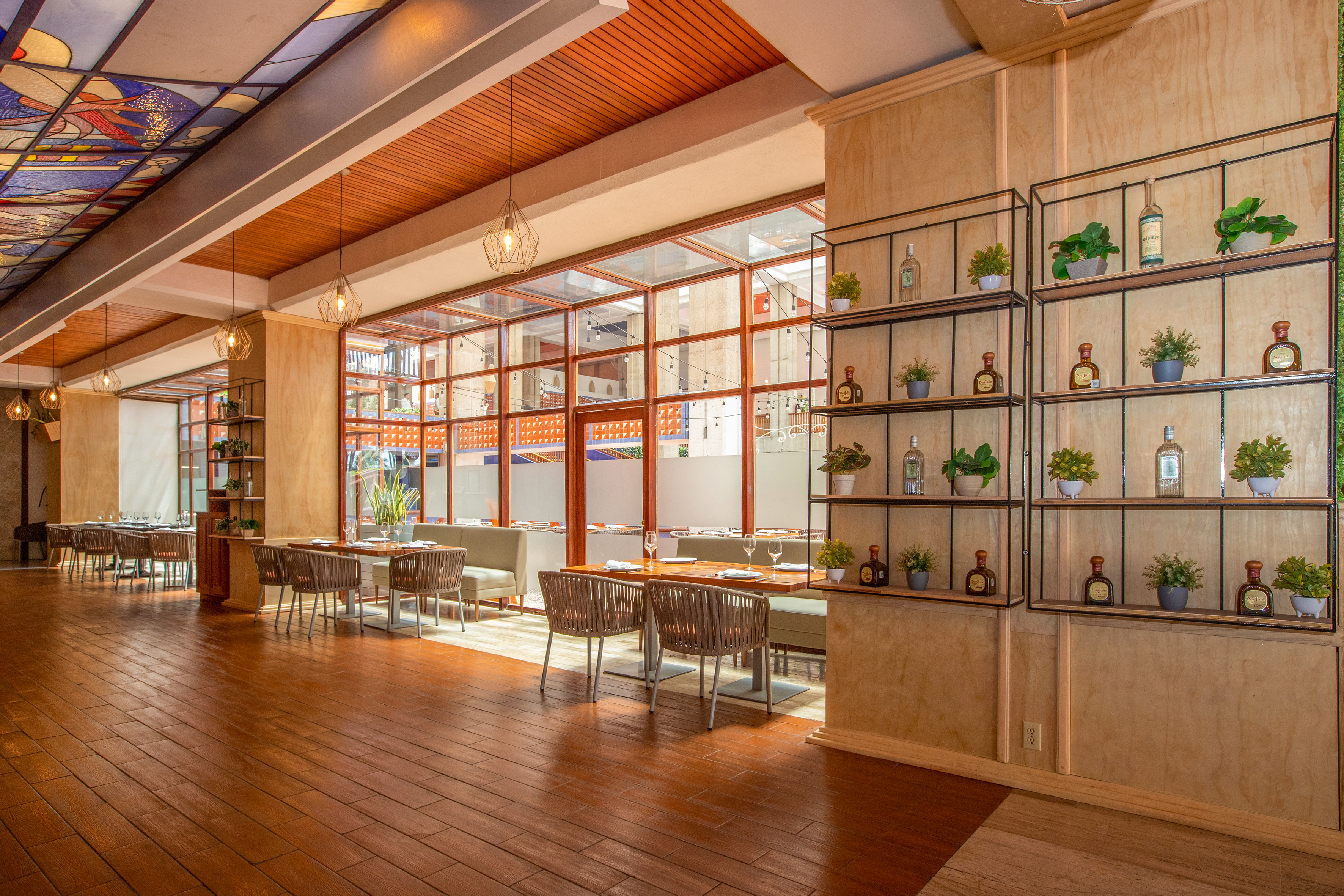 Modern restaurant with wood floor, glass walls, stained glass, and decorative shelves.
