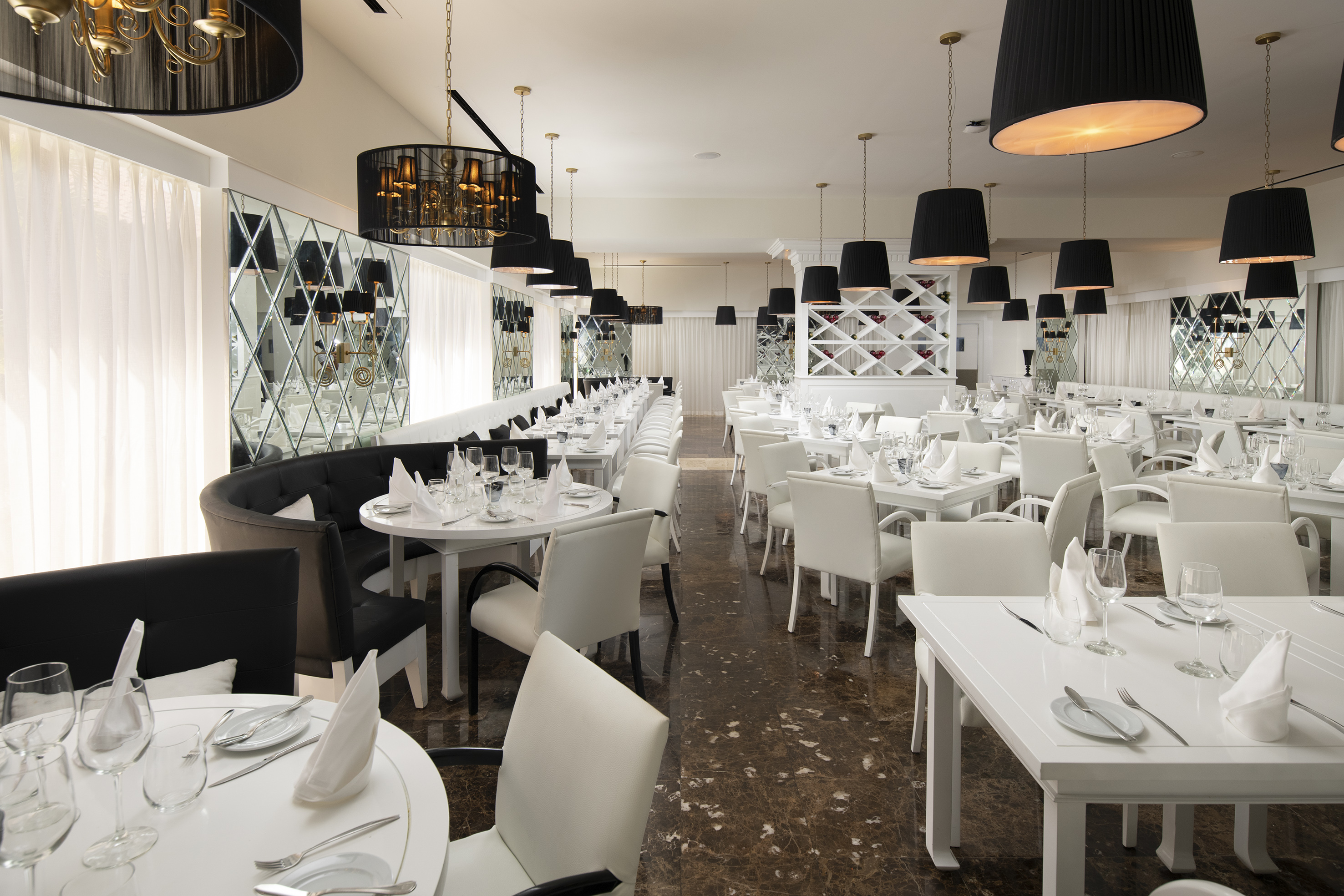 Elegant restaurant dining room, black chandeliers, white tables, modern decor.