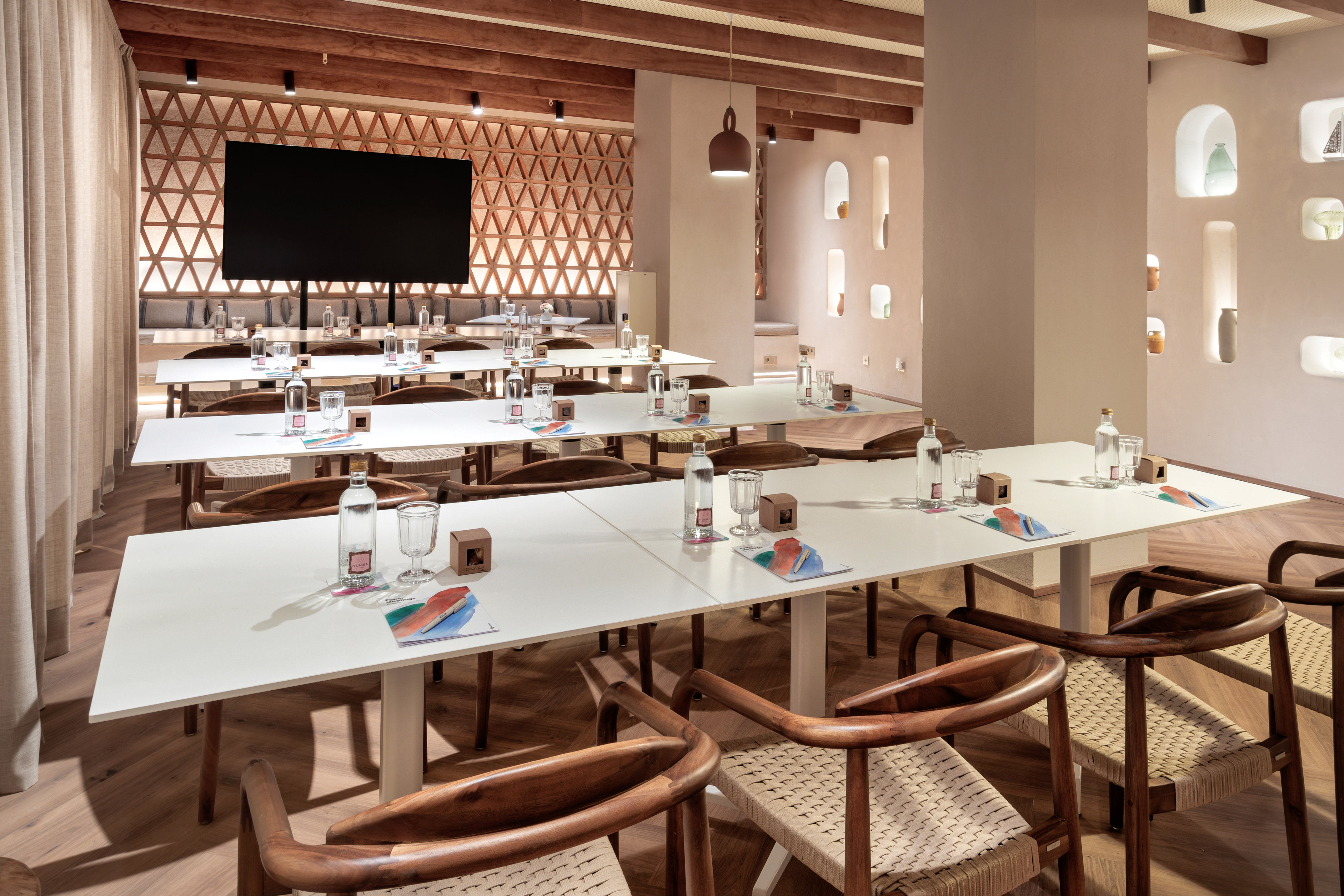 Contemporary conference room with white tables, wooden chairs, and large TV.