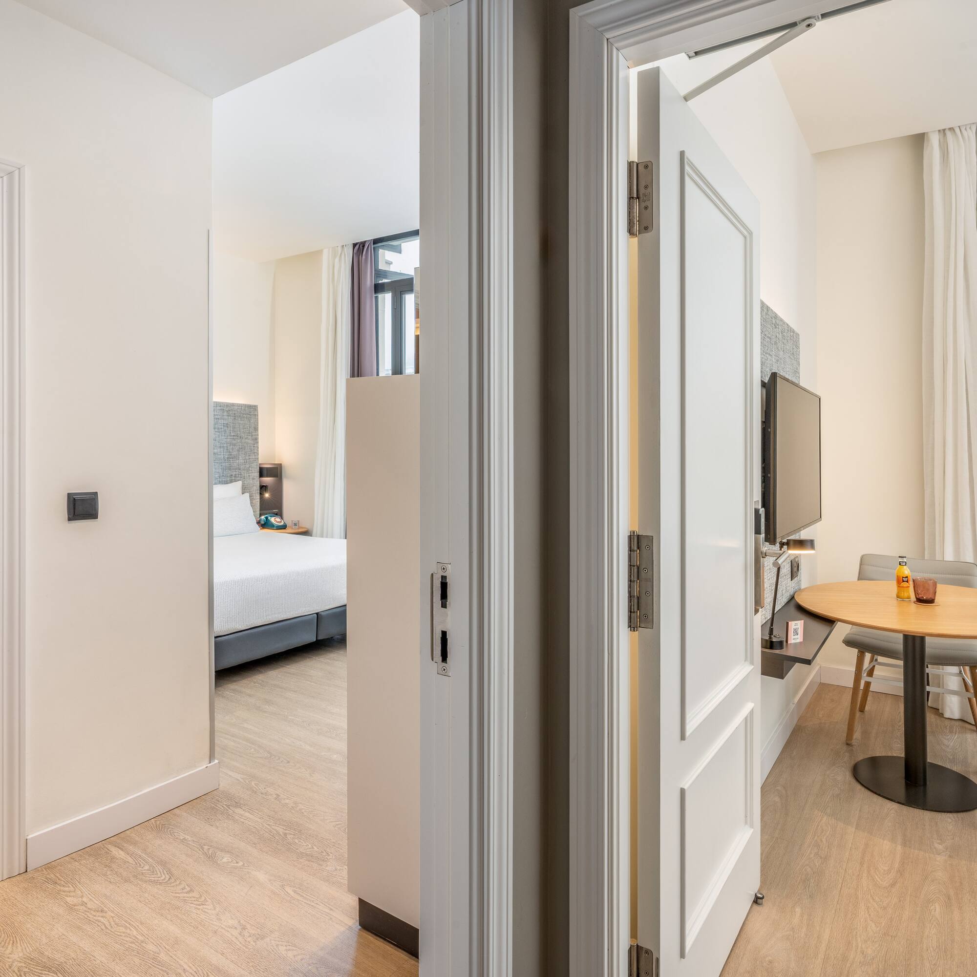 Bright hotel suite with bedroom, dining area, and bathroom.