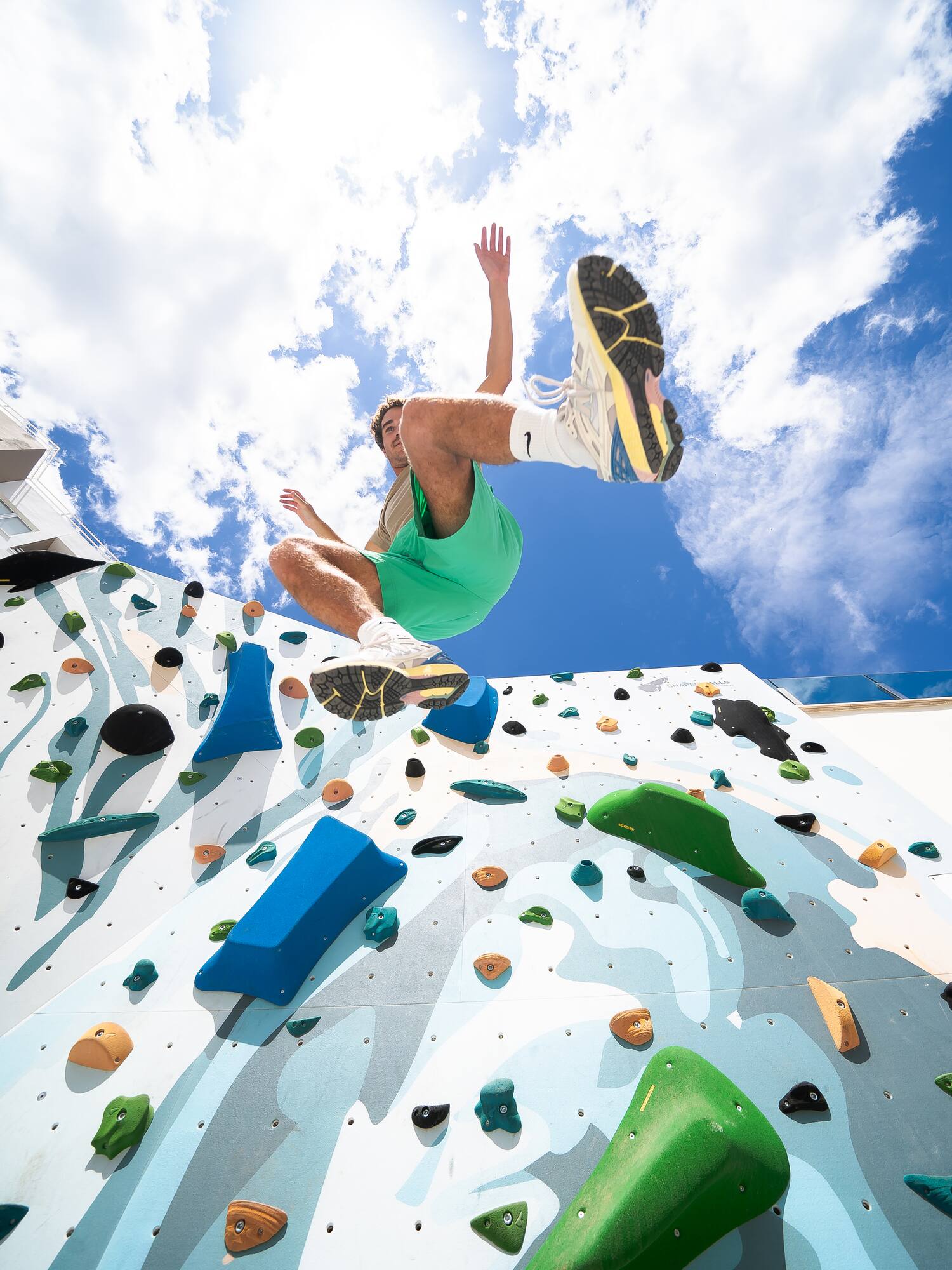 a man jumping over a rock climbing wall