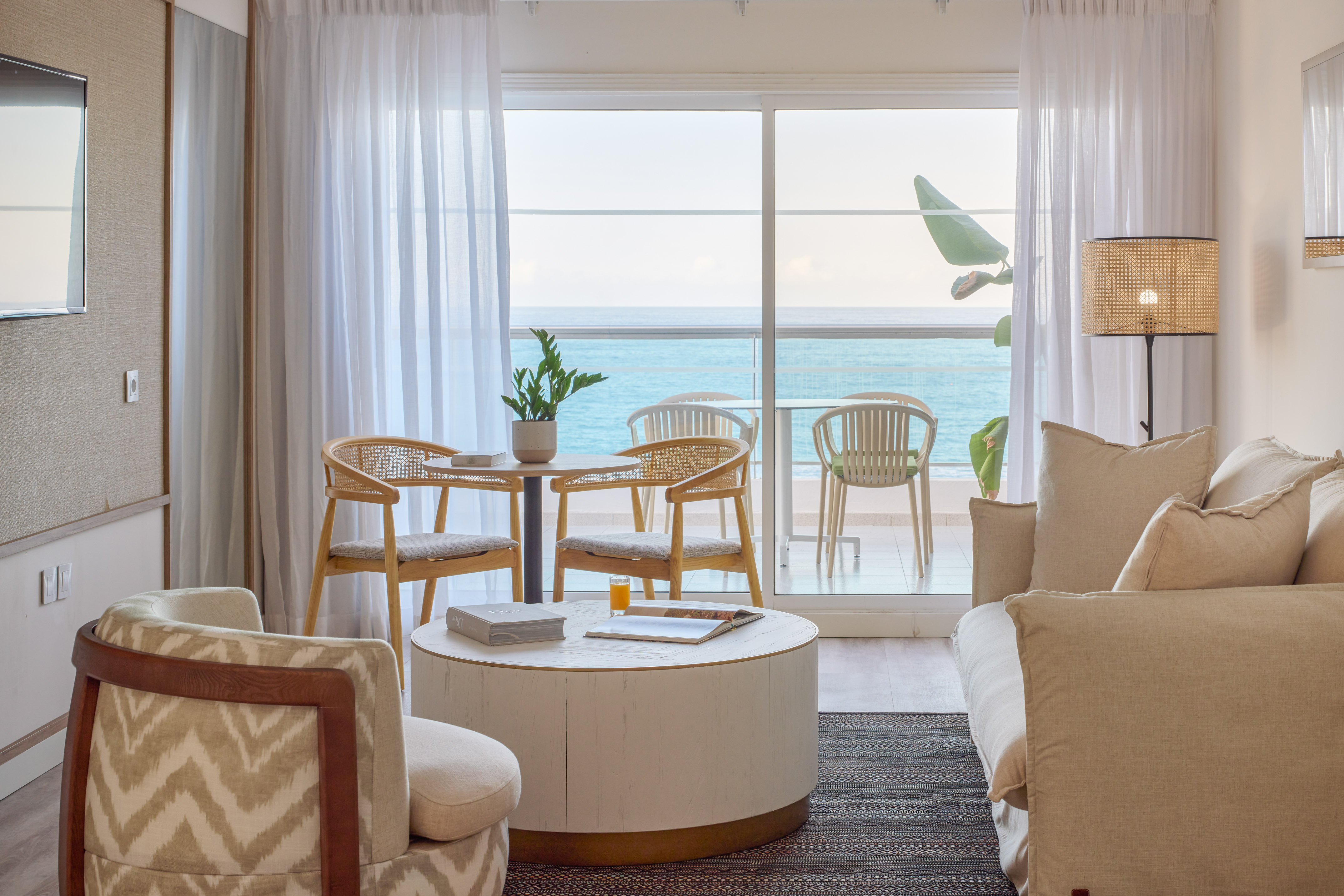 Modern hotel suite living room with ocean view balcony and stylish furniture.