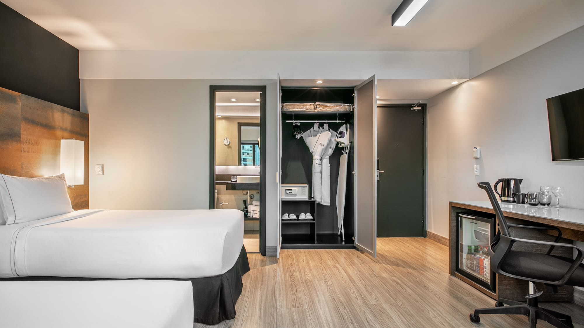 Quarto de hotel moderno com duas camas, armário aberto e mesa de trabalho. - Deluxe Room Twin - Meliá Ibirapuera, São Paulo
