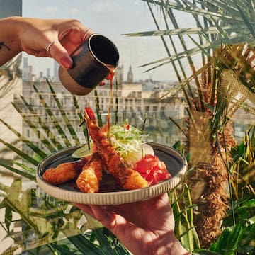 a person pouring sauce onto a plate of food