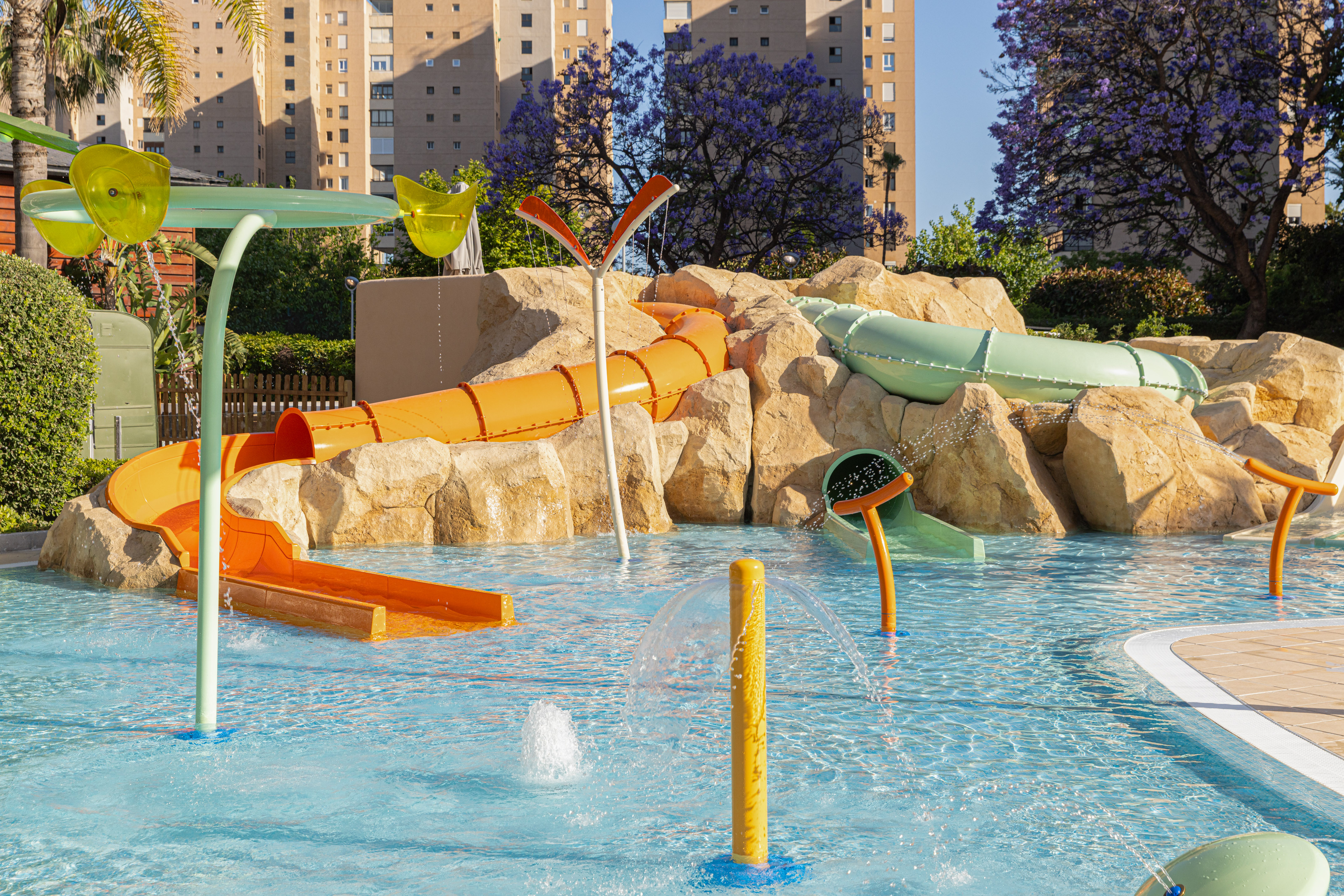 Kids' water park with colorful slides, splash pad, and rock features.