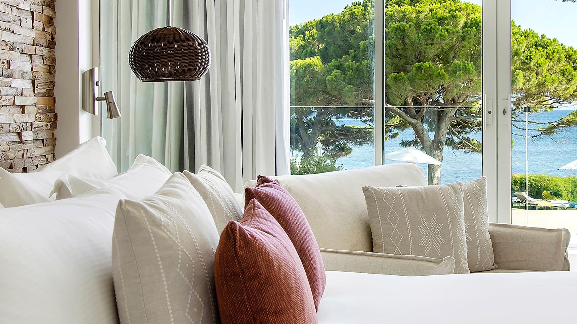 a bed with pillows and a lamp in front of a large window